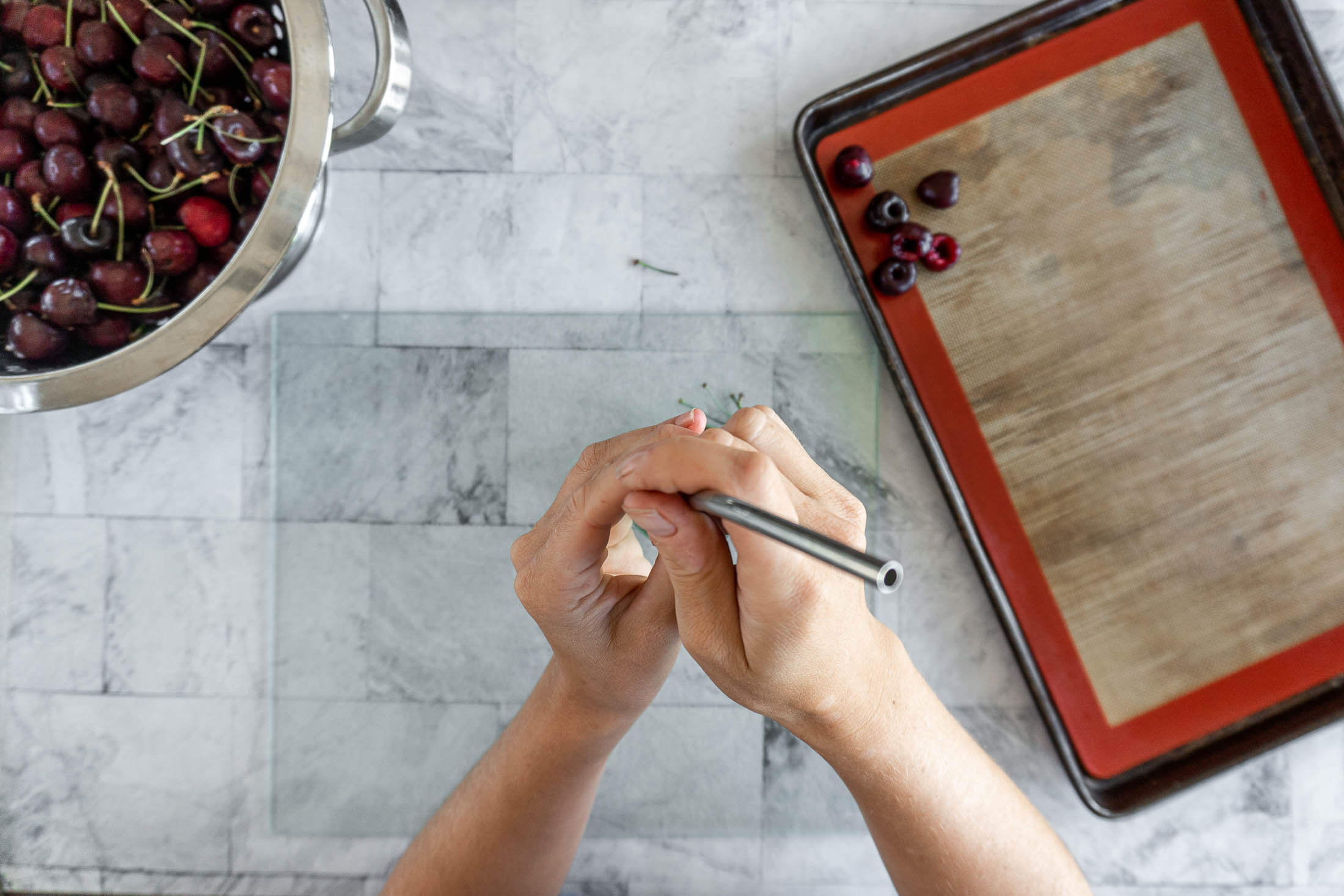 Punching the pit out of the cherry with a stainless steel straw.