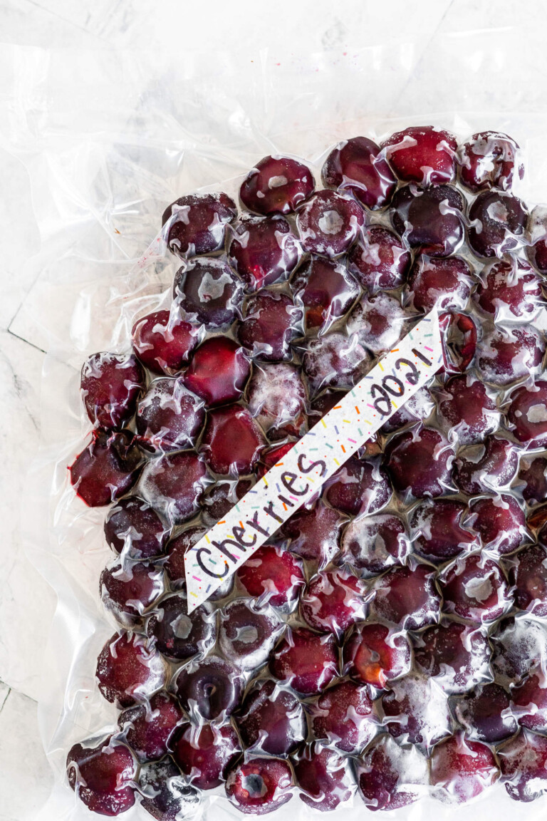 A vacuum sealed bag of frozen cherries labeled with the contents and the date.