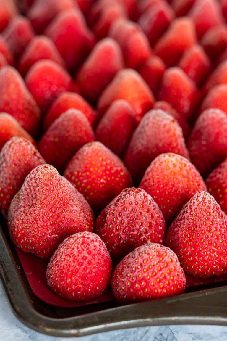 Frozen whole strawberries on a baking sheet.