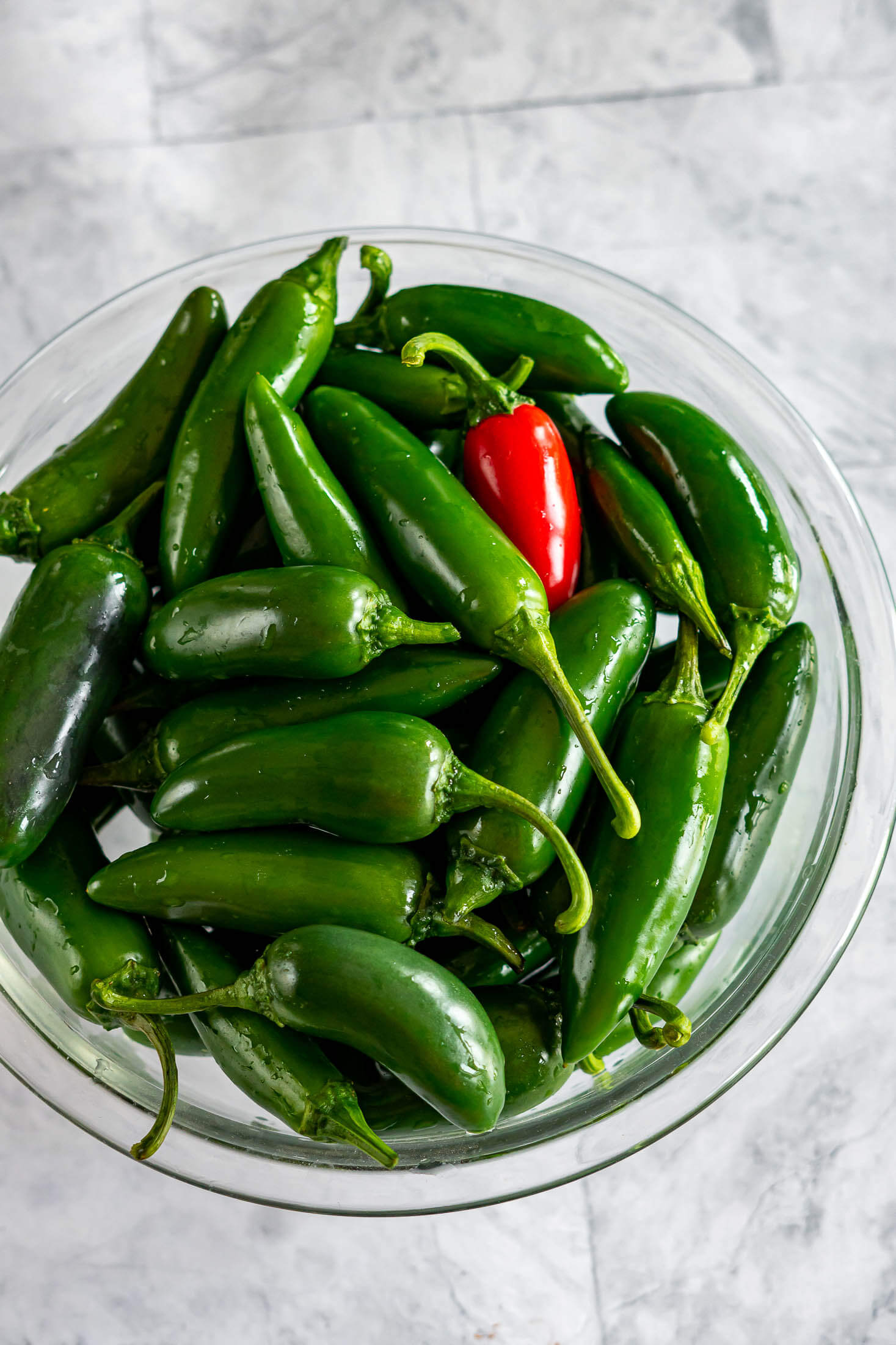 Large glass bowl piled high with fresh garden jalapeños.
