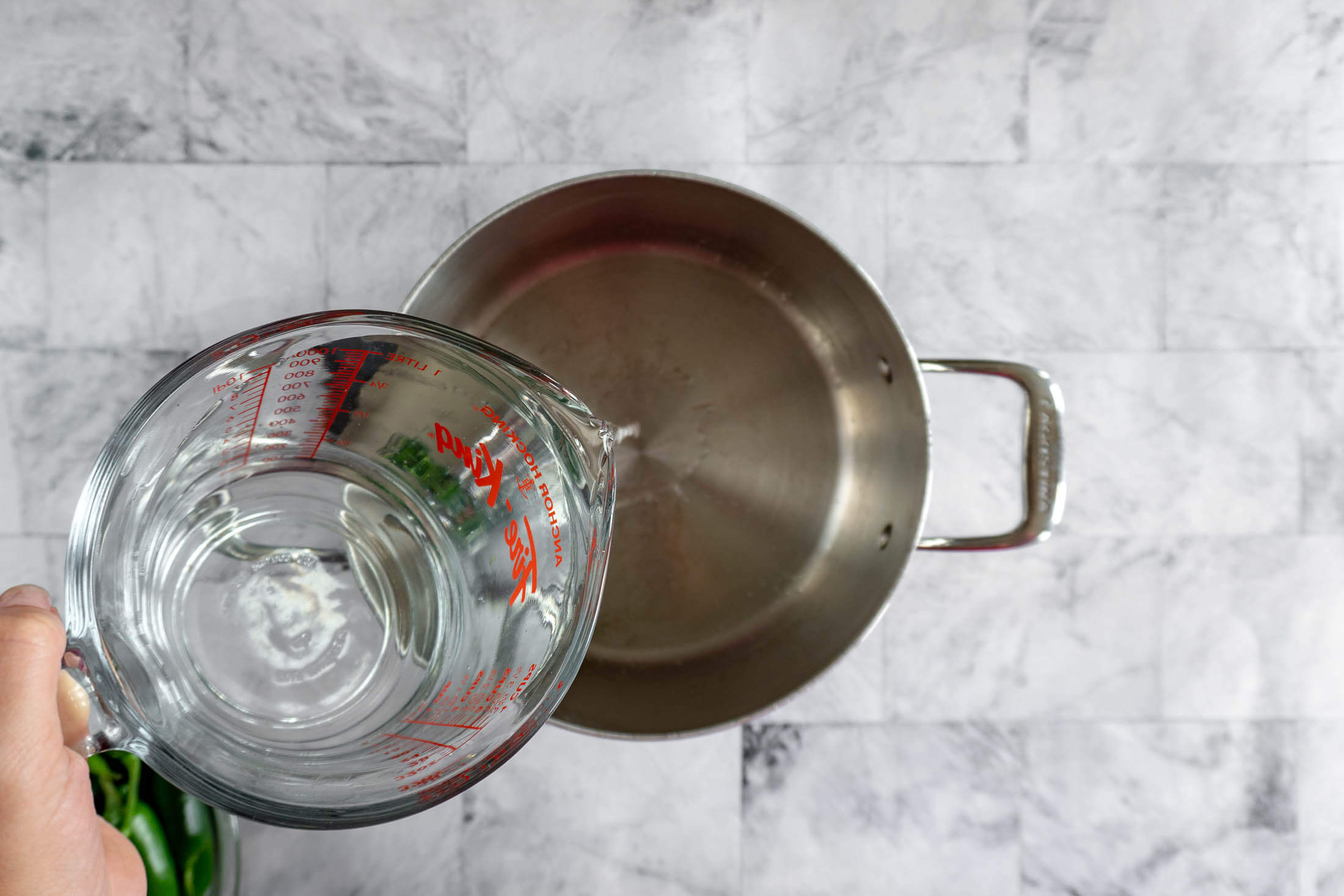 Pouring white vinegar into a saucepan to start the pickling brine. 