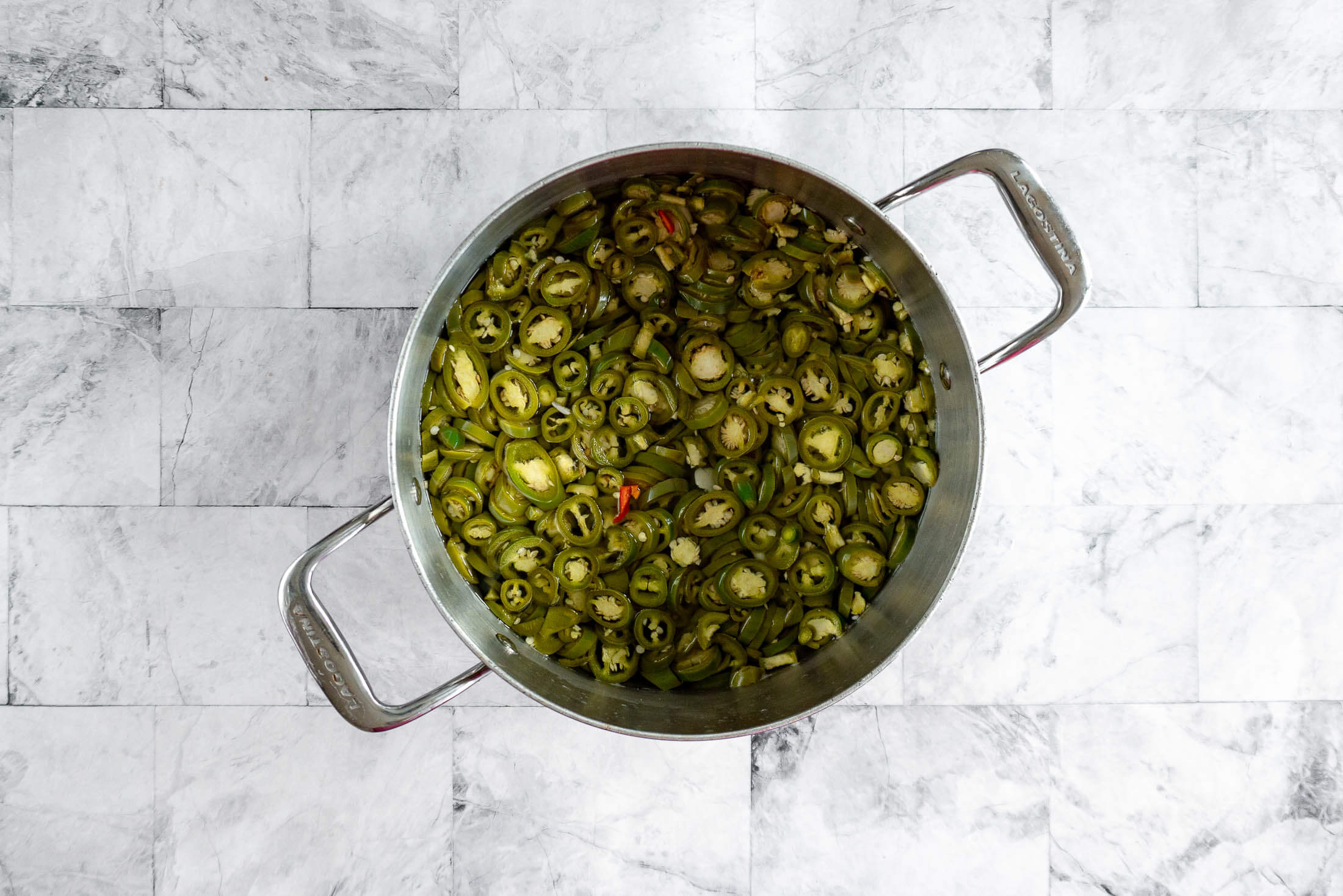 Jalapeno rings turning a deeper-olive green after soaking in the hot brine. 