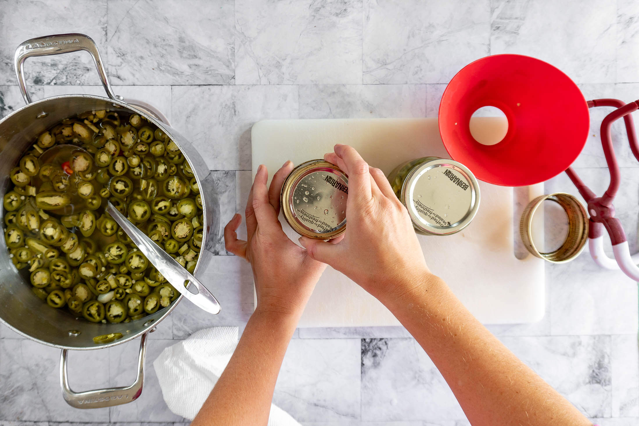 Tightening a canning lid and band to finger-tight on a filled jar. 