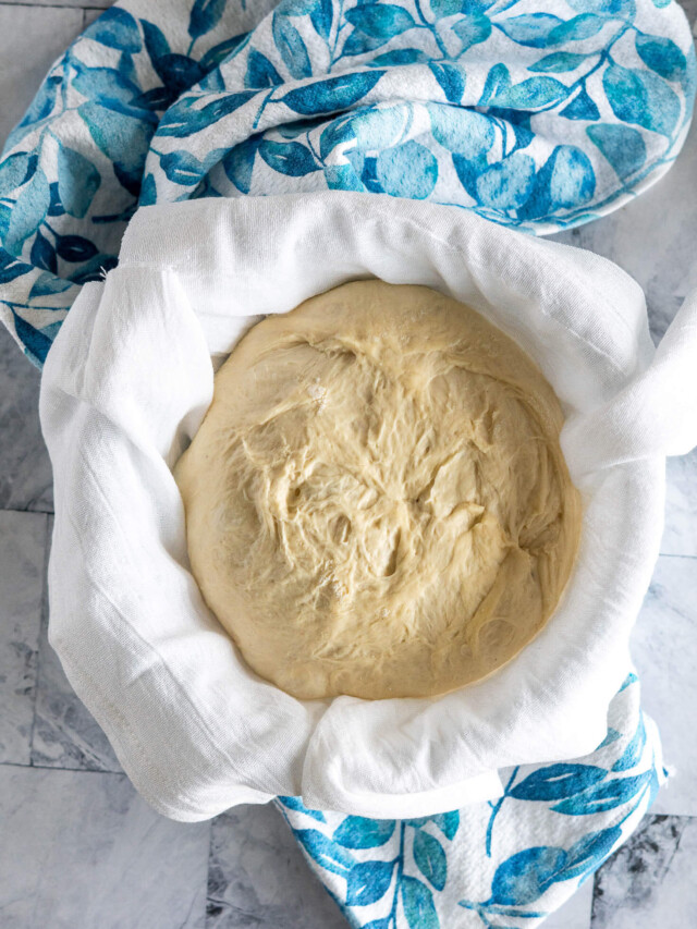 Proofing dough in glass bowl lined with flour sack towel.