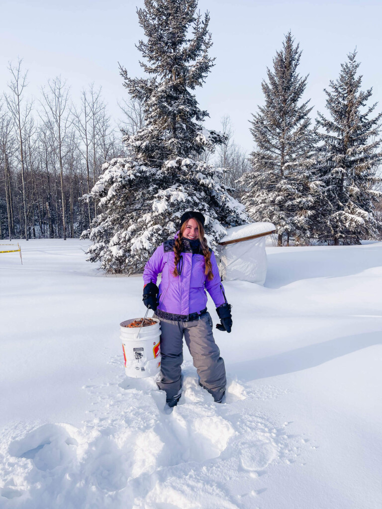 A woman holding a compost bucket in the snow.