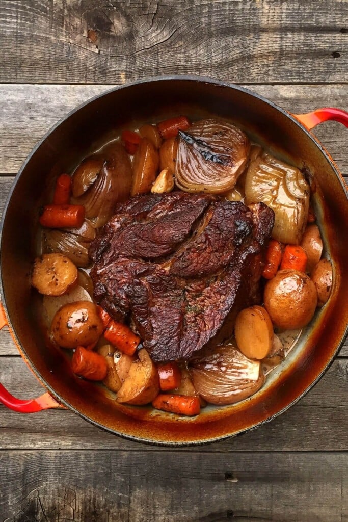 Pot roast in a red cast iron dutch oven.