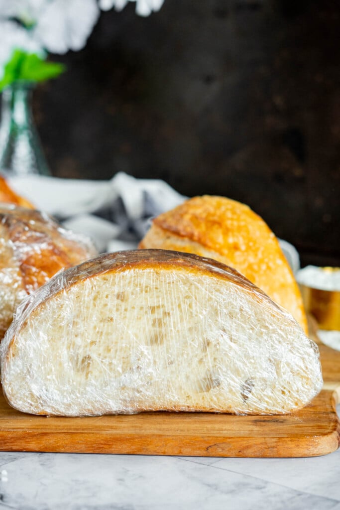 A plastic wrapped half loaf of sourdough.