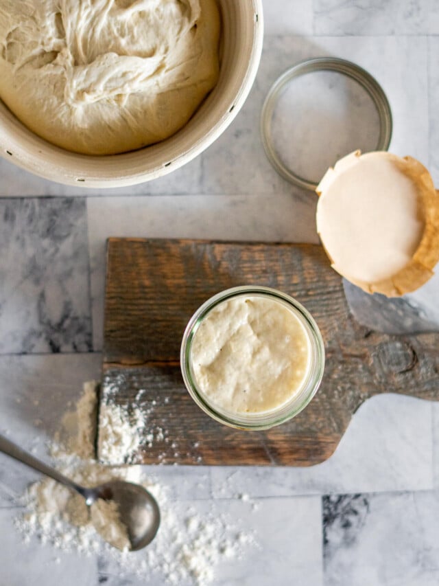 Overhead view of starter in a jar with sourdough in a banneton.