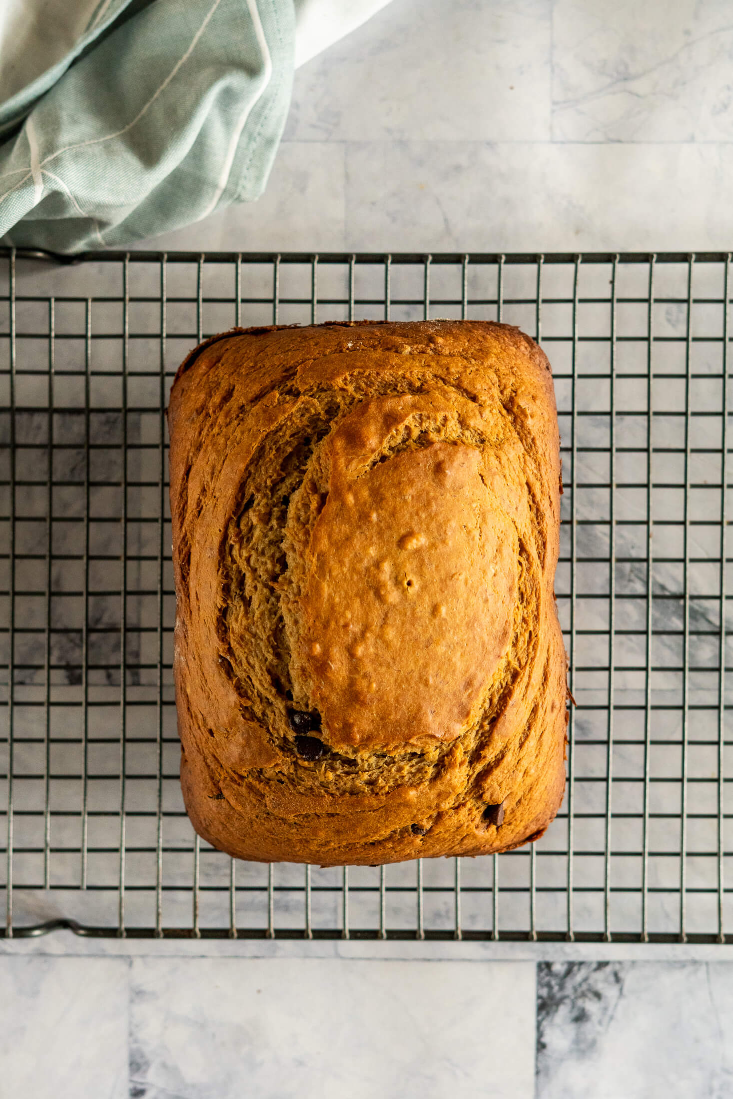 Bread machine banana bread loaf cooling a black wire mesh rack after baking.