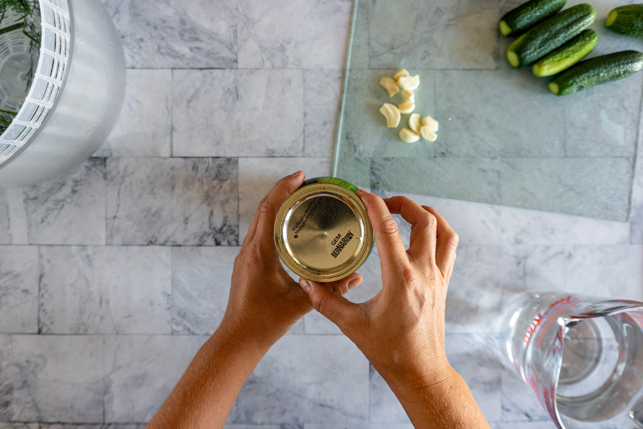 Securing the lid on a jar of cucumbers prepared for fermentation.