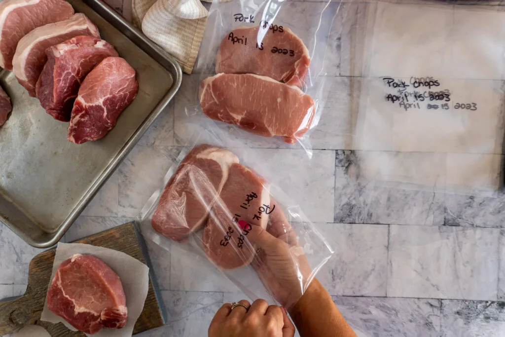 Placing raw pork chops in vacuum seal bag.