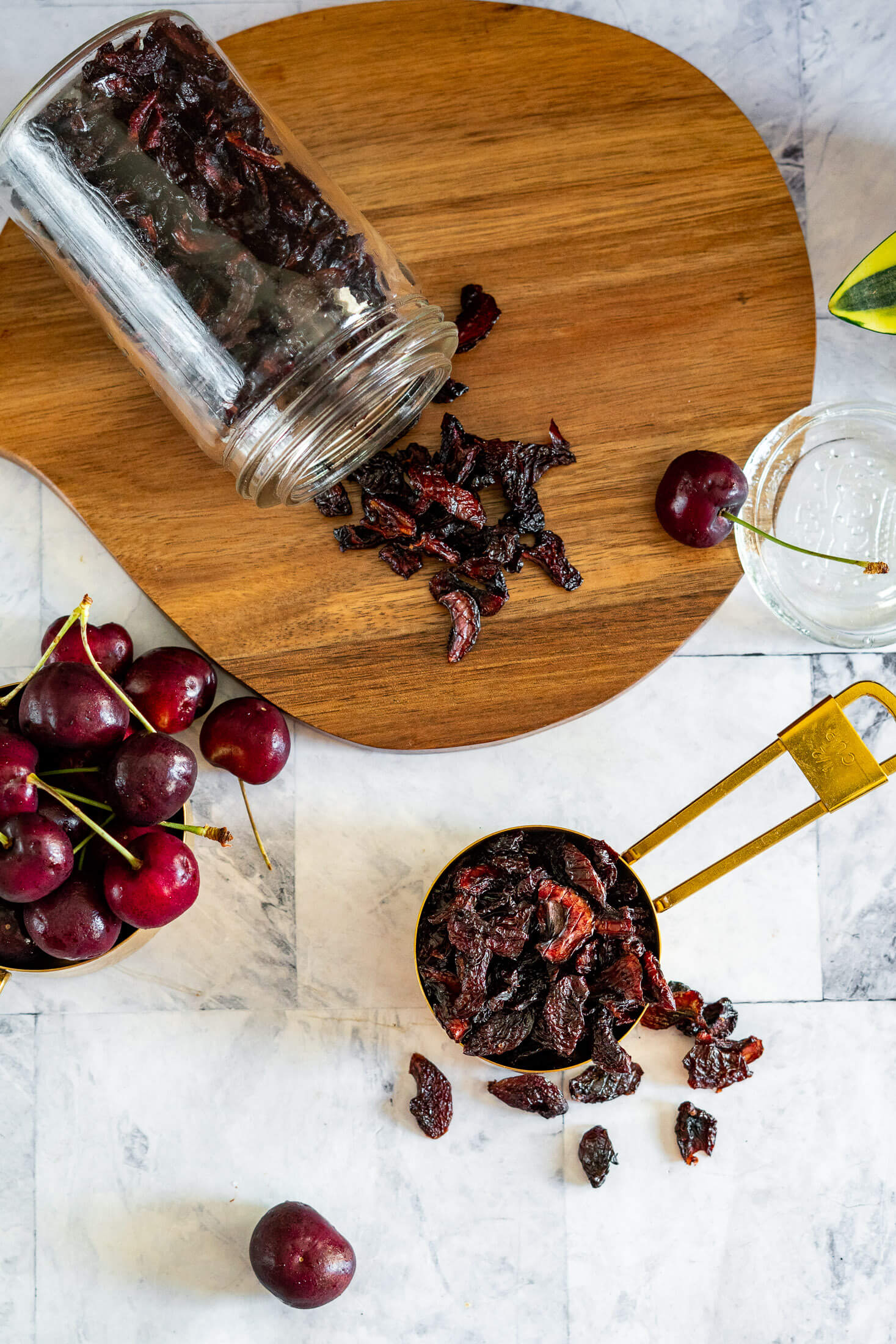 Dried cherries in a mason jar and gold measuring cup.