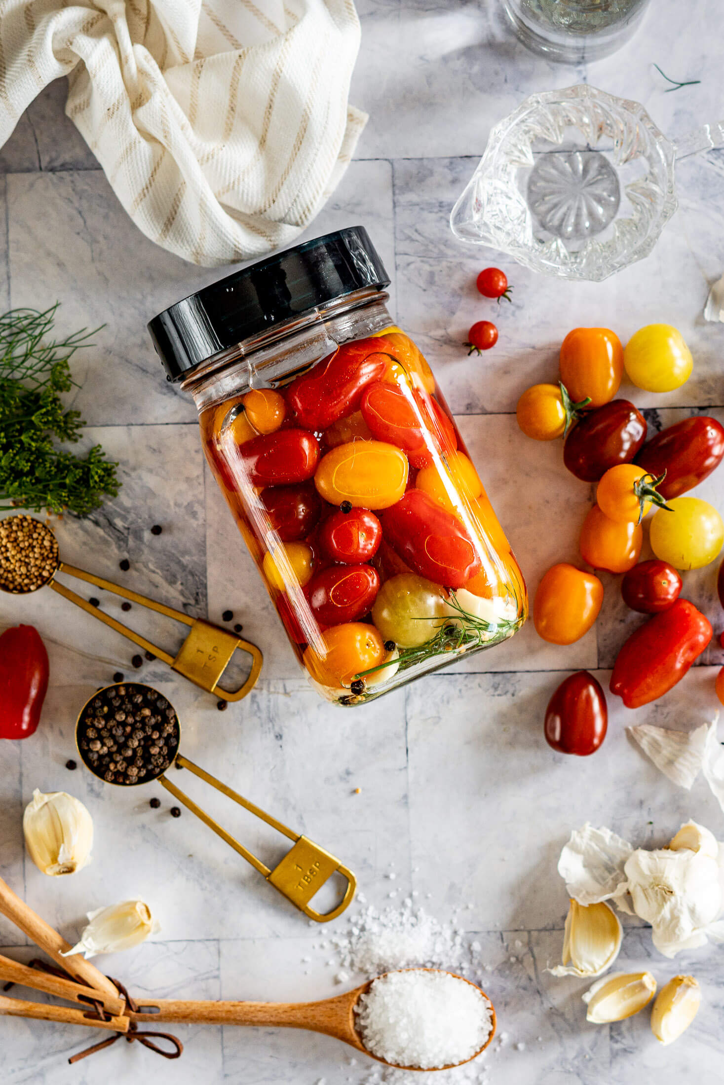 Jar of lacto fermented cherries surrounded by the ingredients needed to make.