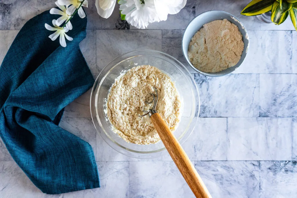 Mixing flour into water with dough whisk.