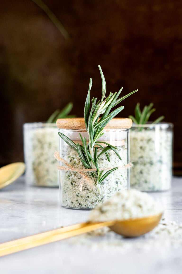 Homemade rosemary salt in glass spice jars.