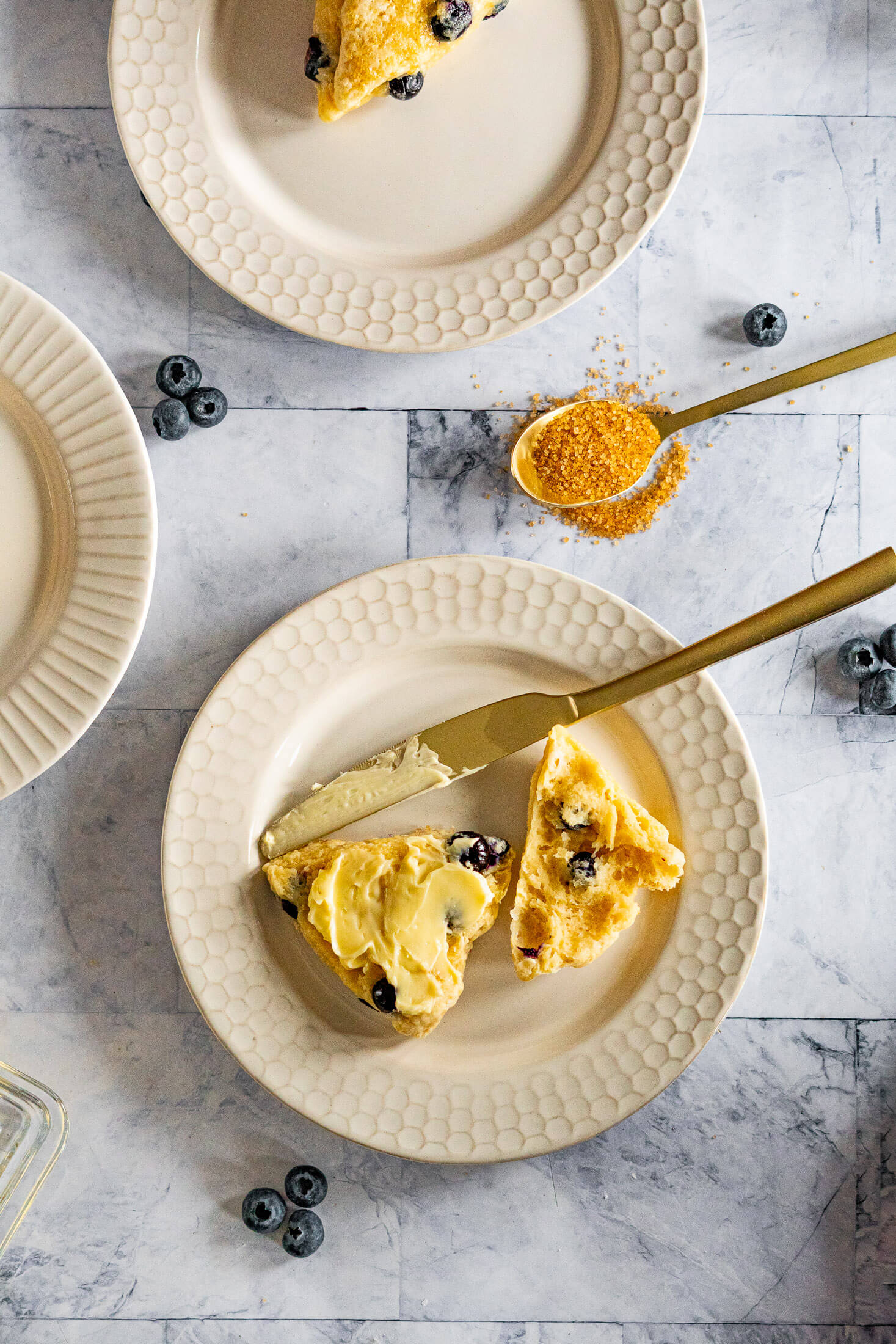 Buttered blueberry scone on a white plate.