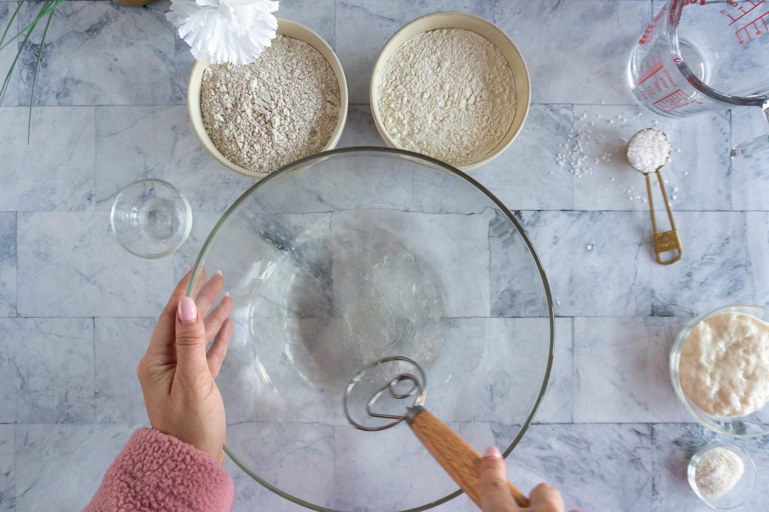 Whisking raw honey into warm water before adding flour for whole wheat sourdough.