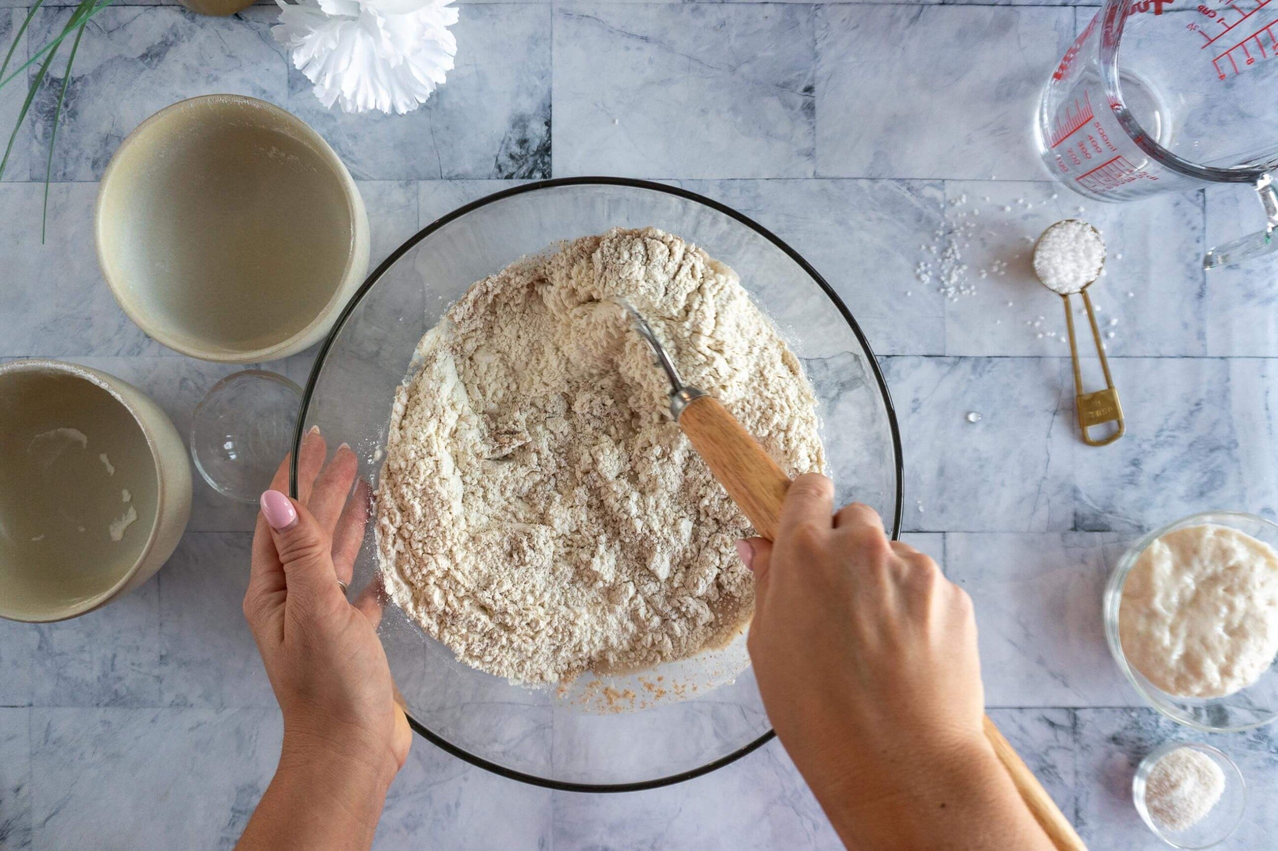 Mixing whole wheat and bread flour into honey water to form sourdough dough.