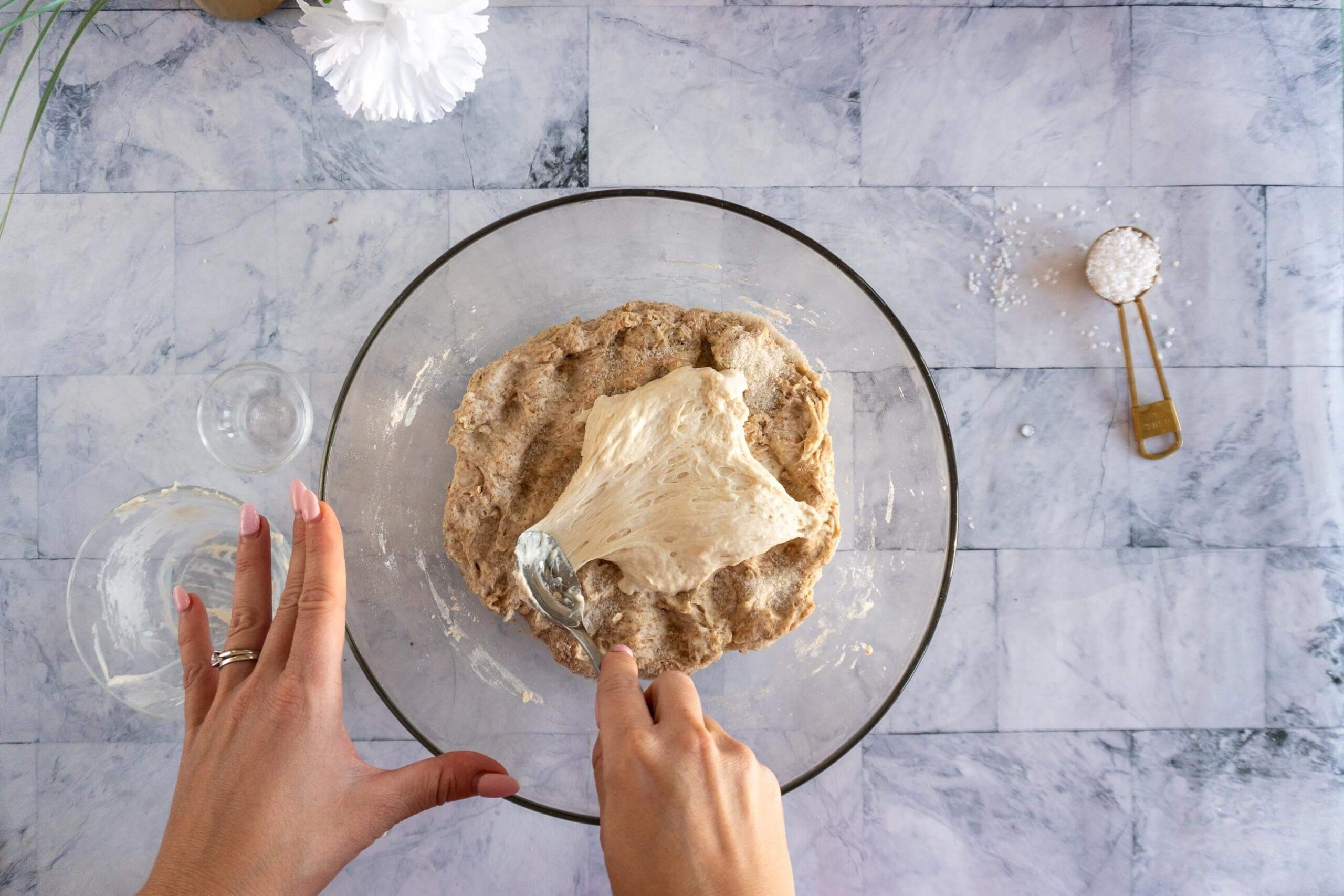 Spreading active sourdough starter across the surface of whole wheat dough.