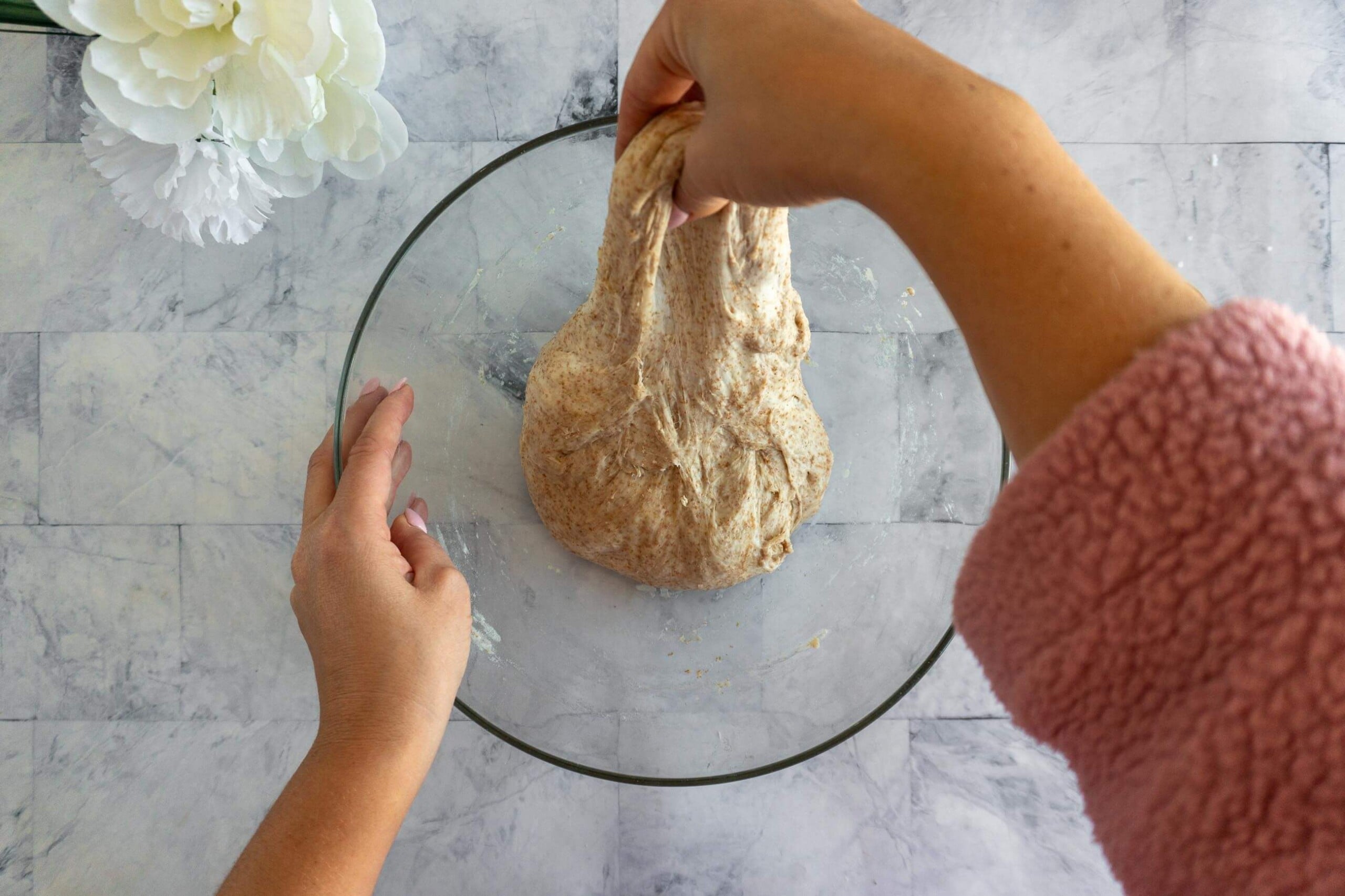 Pressing bulk-fermented whole wheat sourdough dough into a rectangle for shaping.