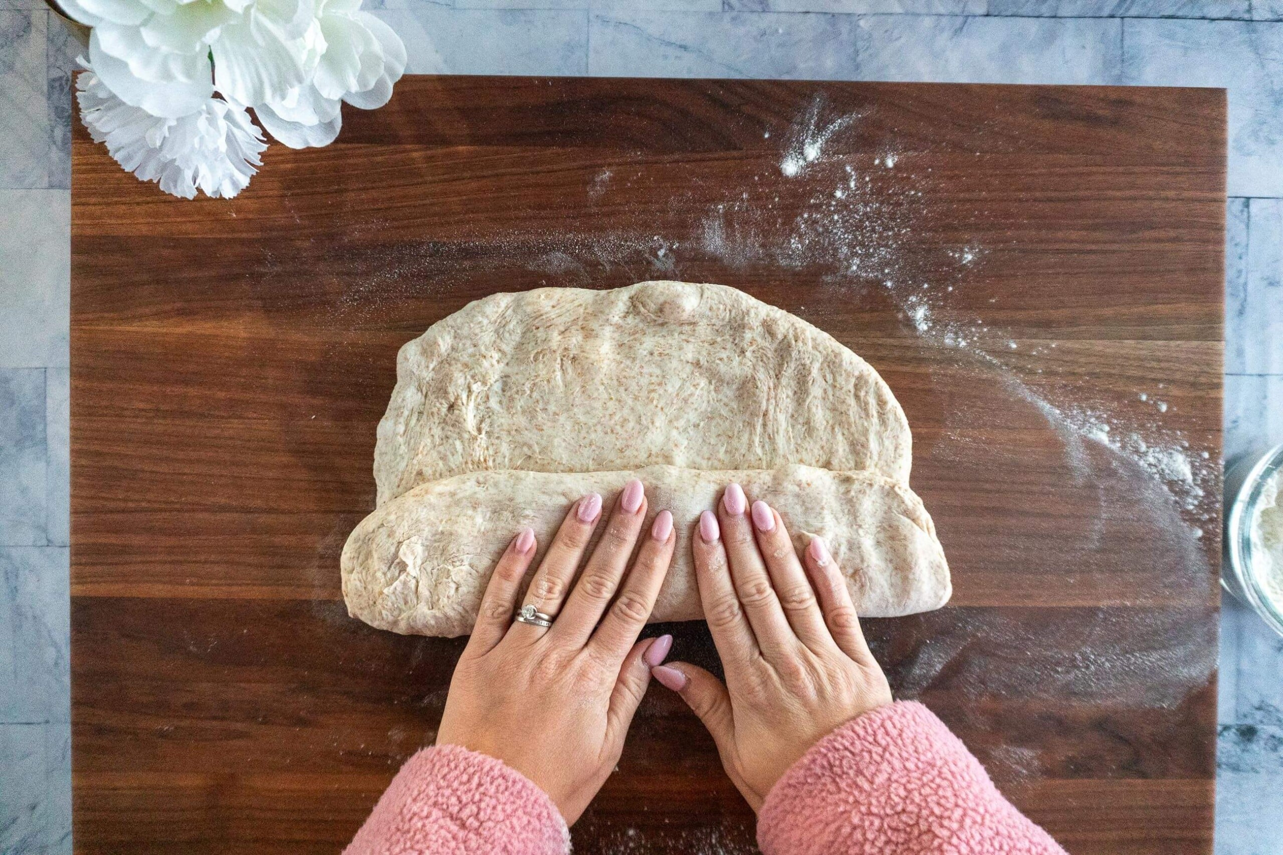 Folding the bottom third of whole wheat sourdough dough like a letter during shaping.