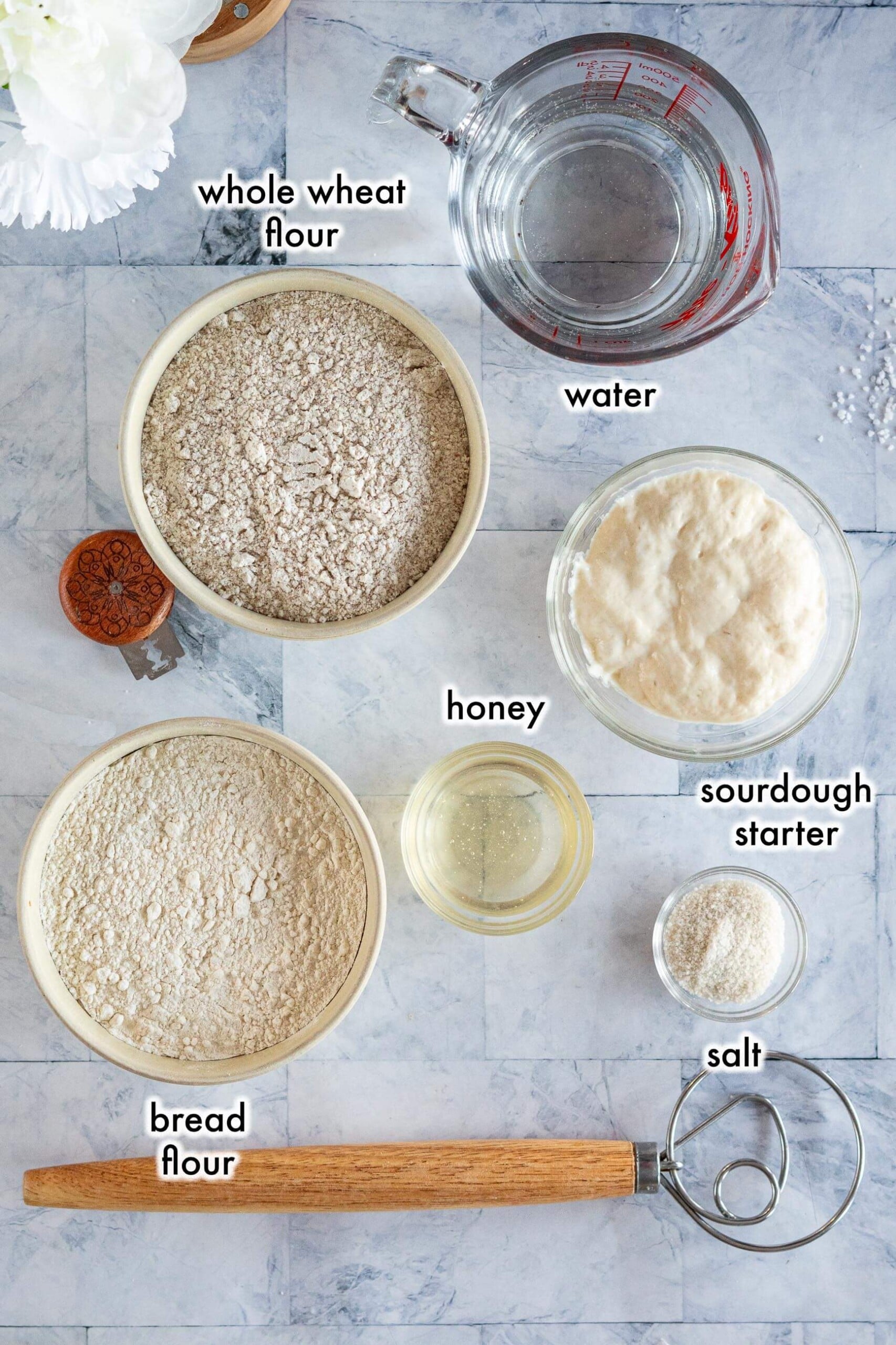 Ingredients for whole wheat sourdough bread including whole wheat flour, bread flour, sourdough starter, honey, salt, and water.