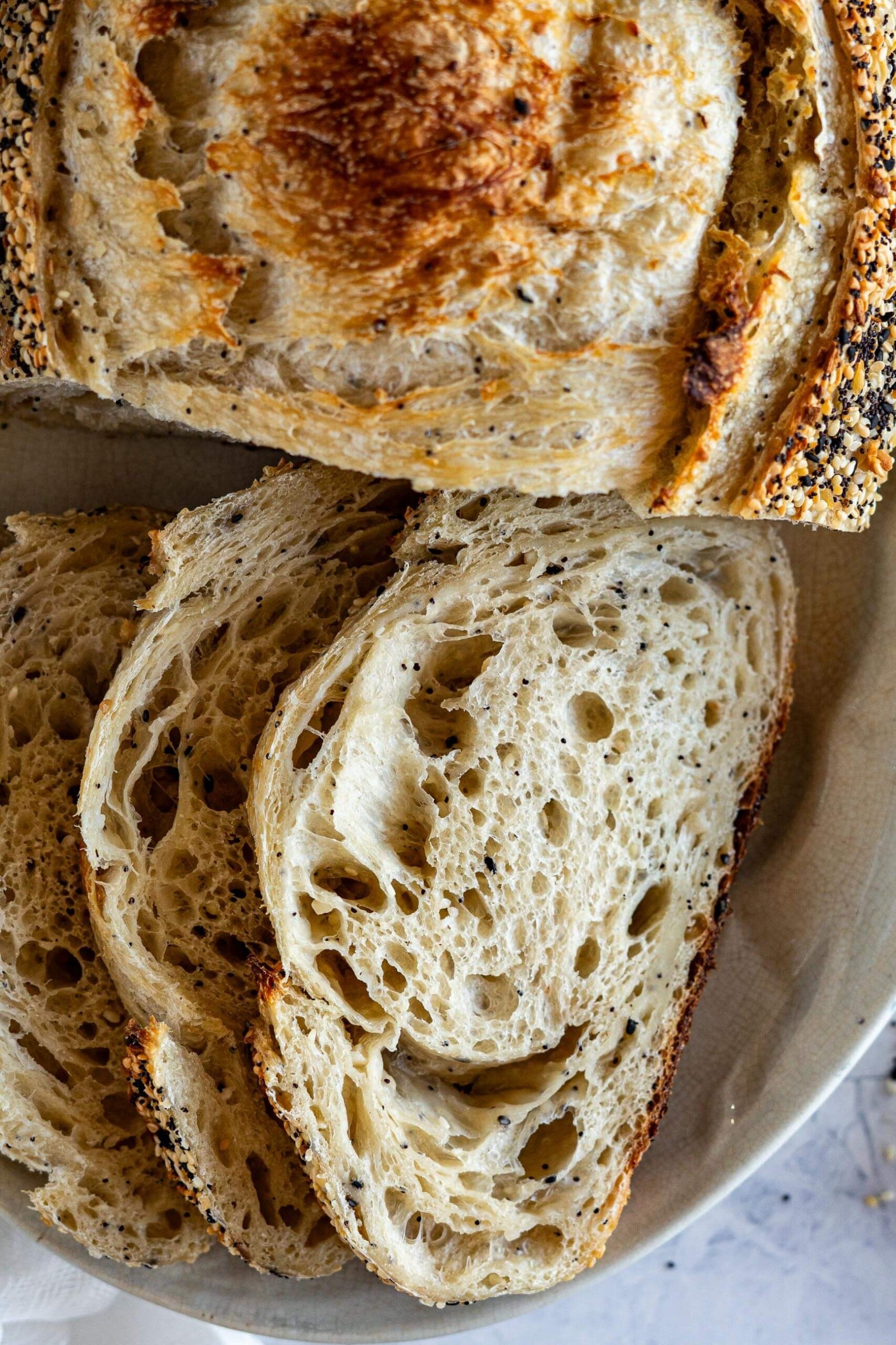 Crumb of the everything bagel sourdough bread dotted with poppy seeds, sesame seeds, dried garlic and dried onions. 