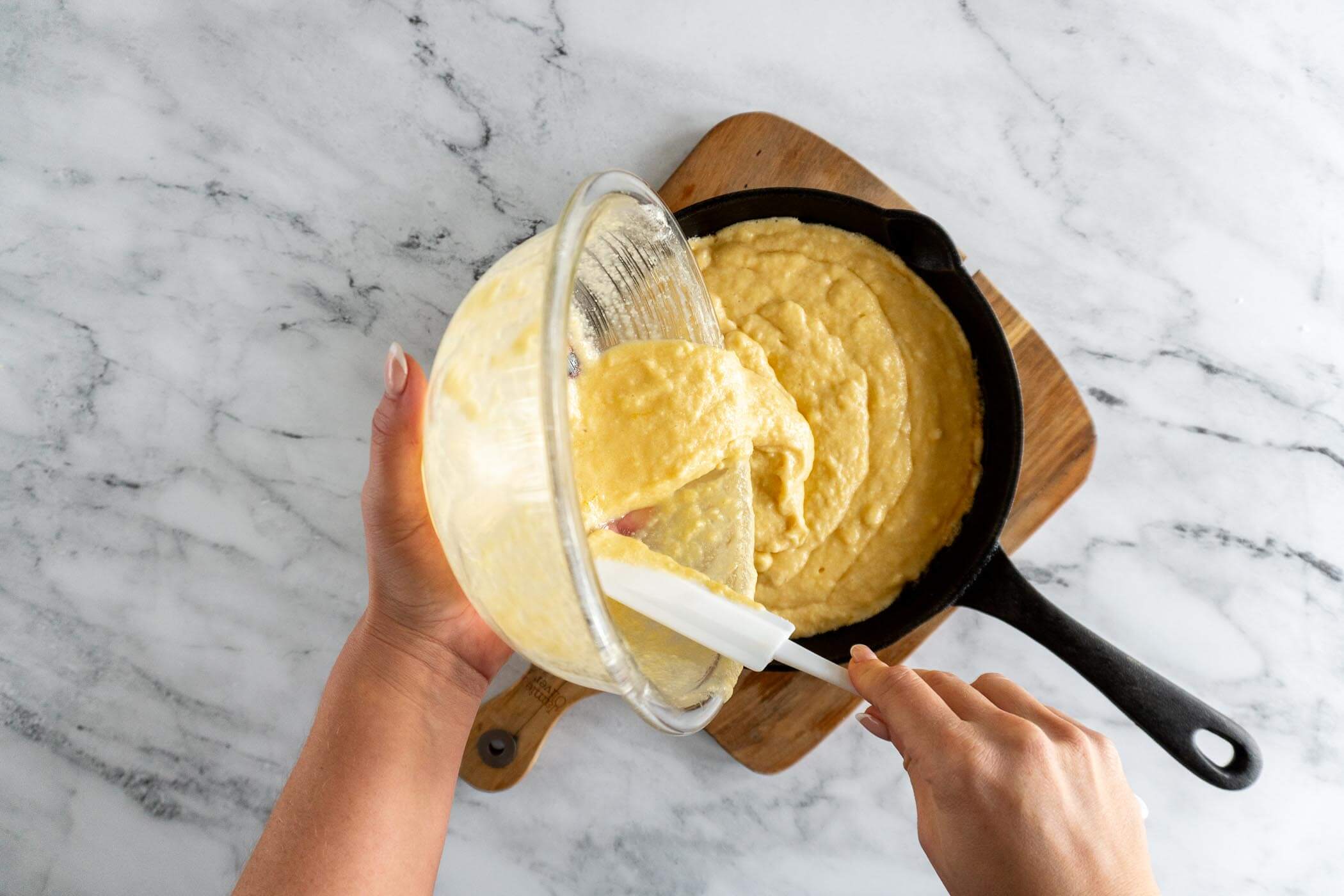 Pouring sourdough cornbread batter into preheated skillet. 