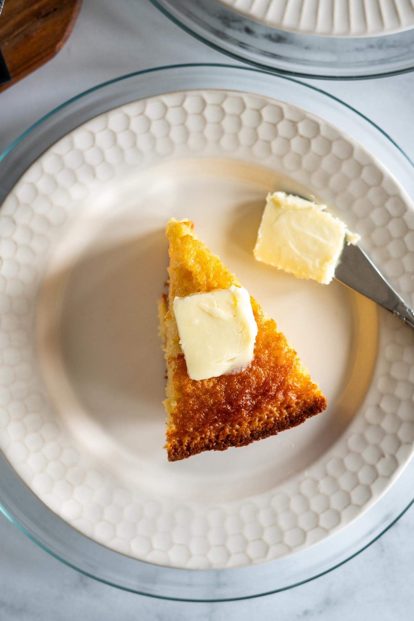 Melting butter on a wedge of sourdough discard cornbread.