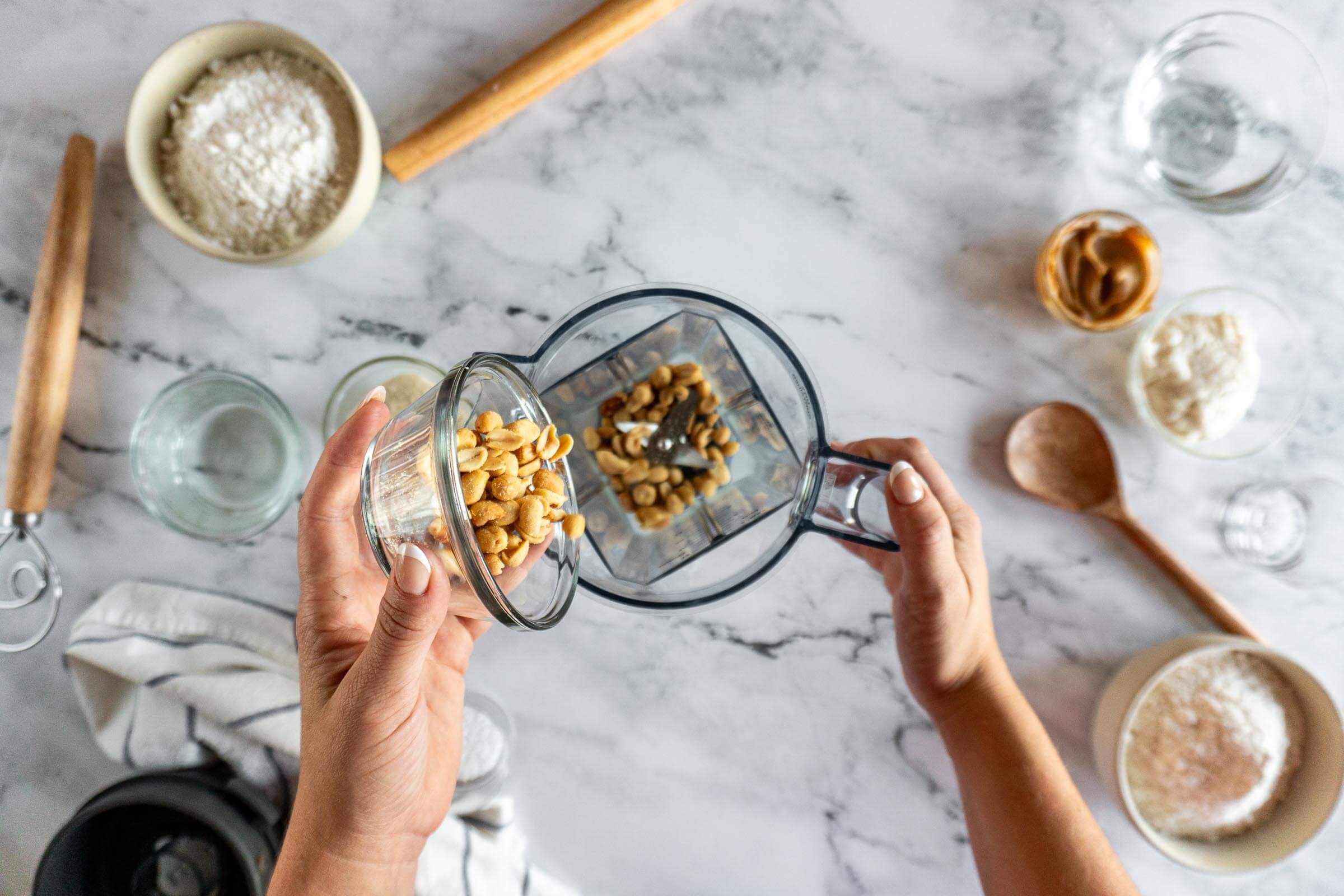 Adding peanuts to blender jar. 