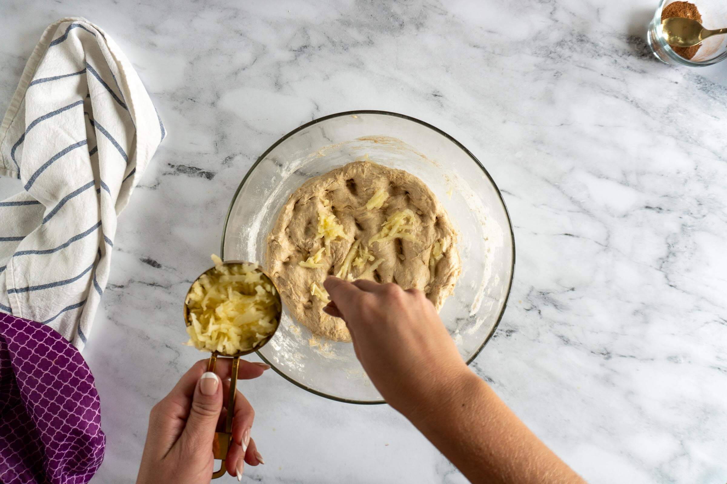 Sprinkling shredded apple on to dimpled dough. 