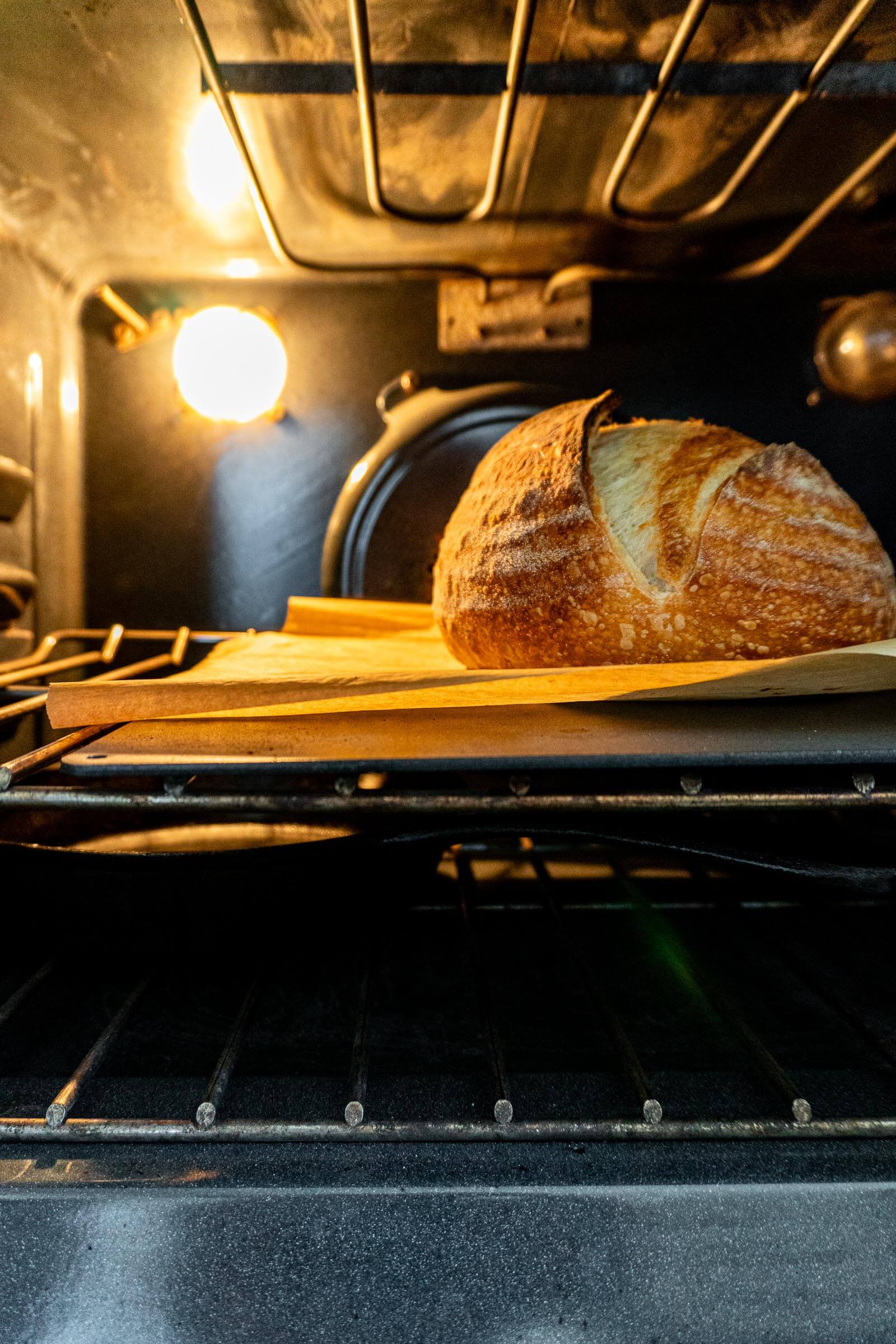 Sourdough loaf baking on pizza steel in oven.