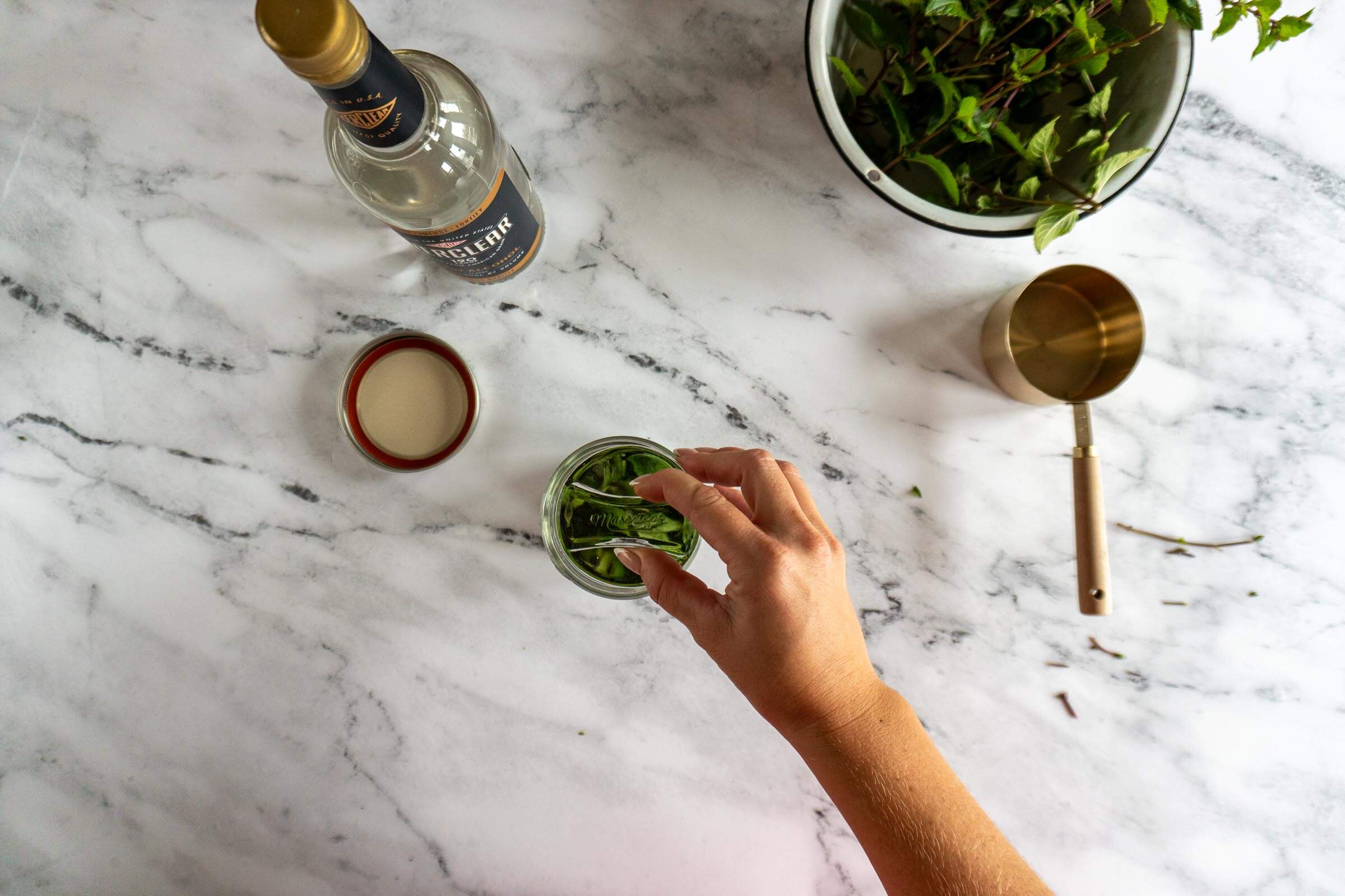 Adding a fermentation weight to the jar to hold down mint leaves.