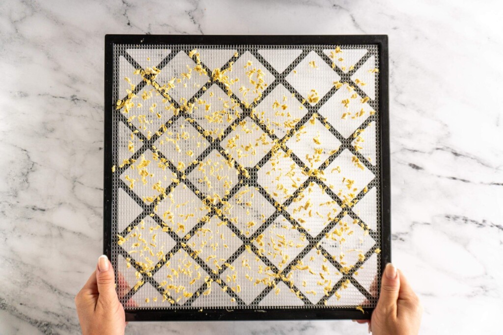 Dried minced ginger on dehydrator rack.