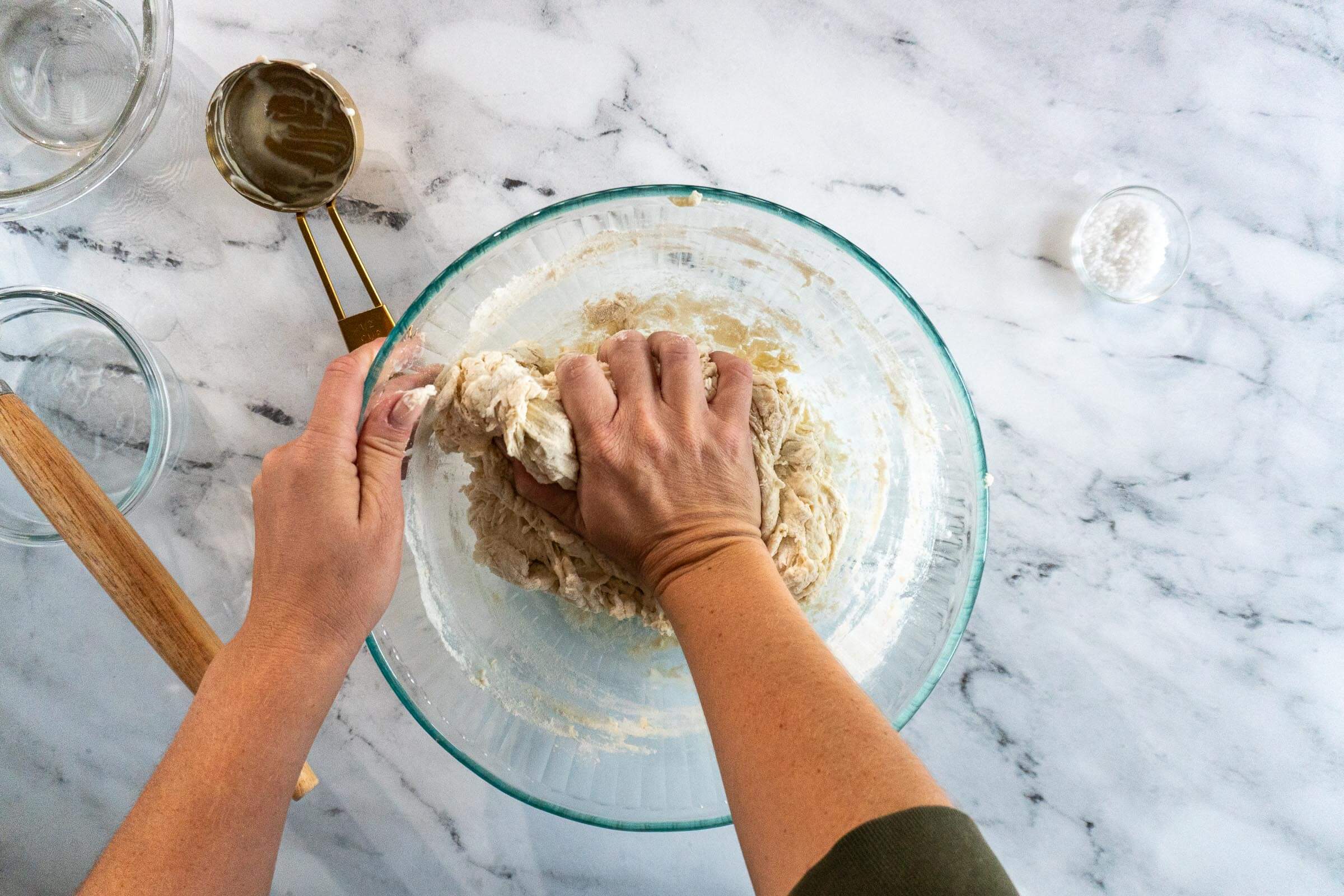 Kneading dry bits of dough by hand.