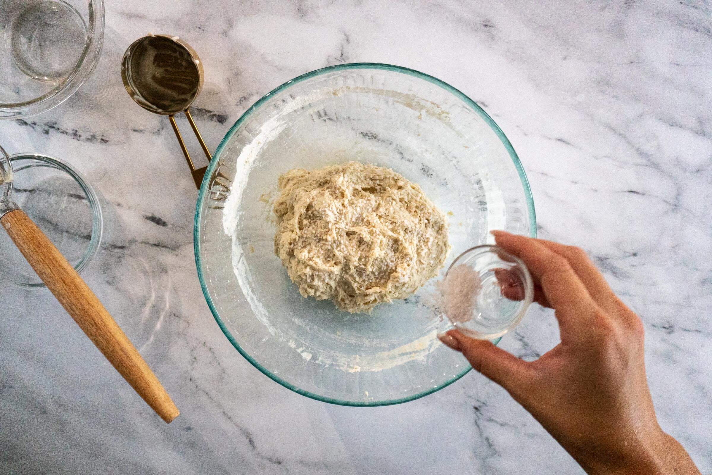 Sprinkling salt on top of kneaded dough.