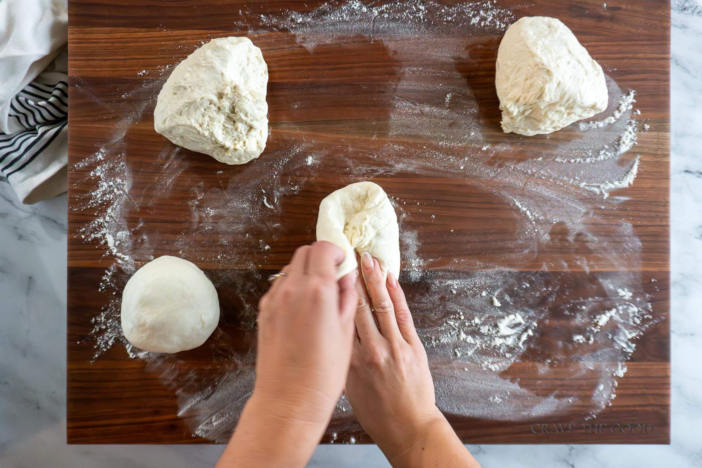 Shaping the dough ball by folding it into itself.