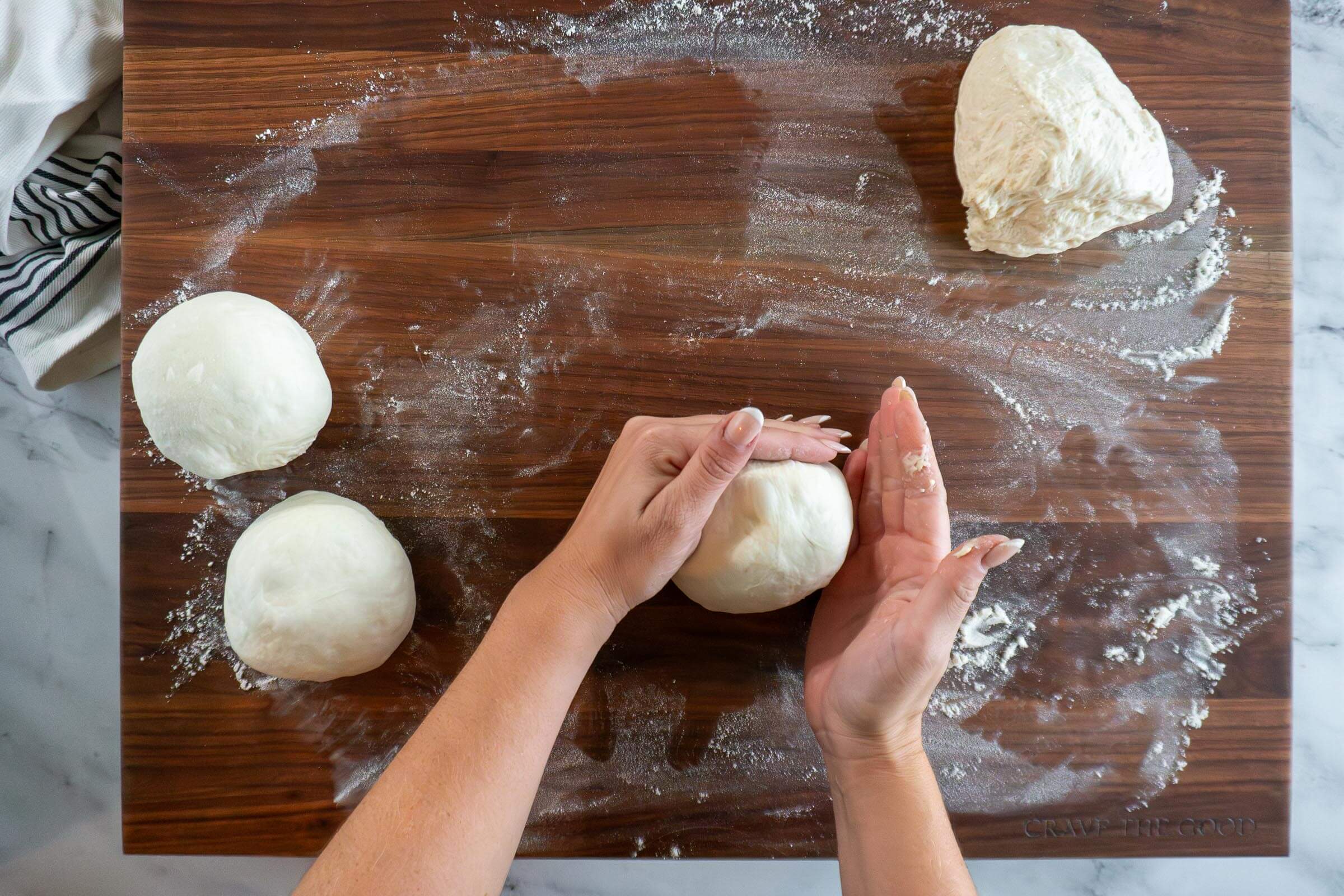 Building surface tension by dragging the dough across the work surface.