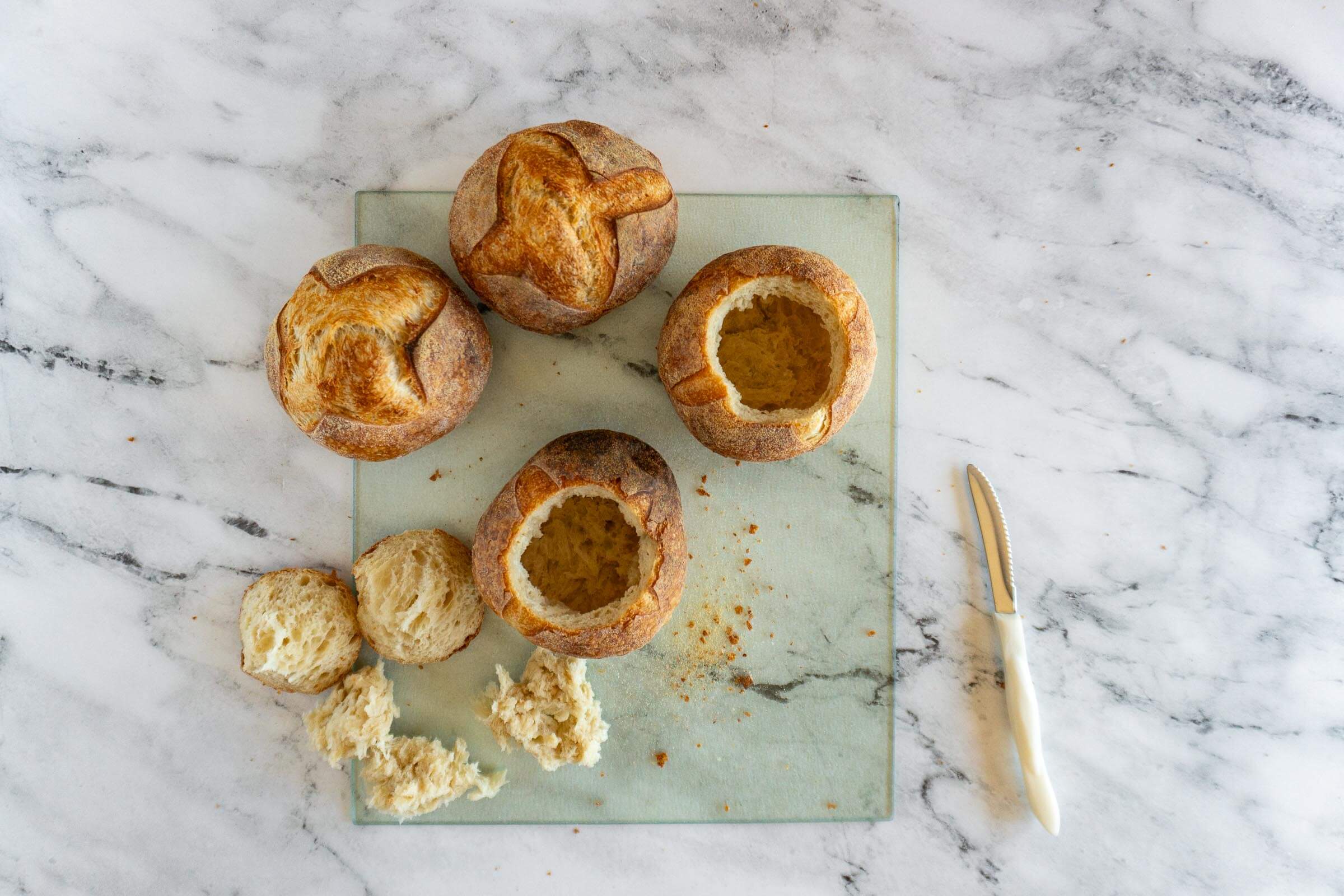 Prepared sourdough bread bowls with reserved tops.