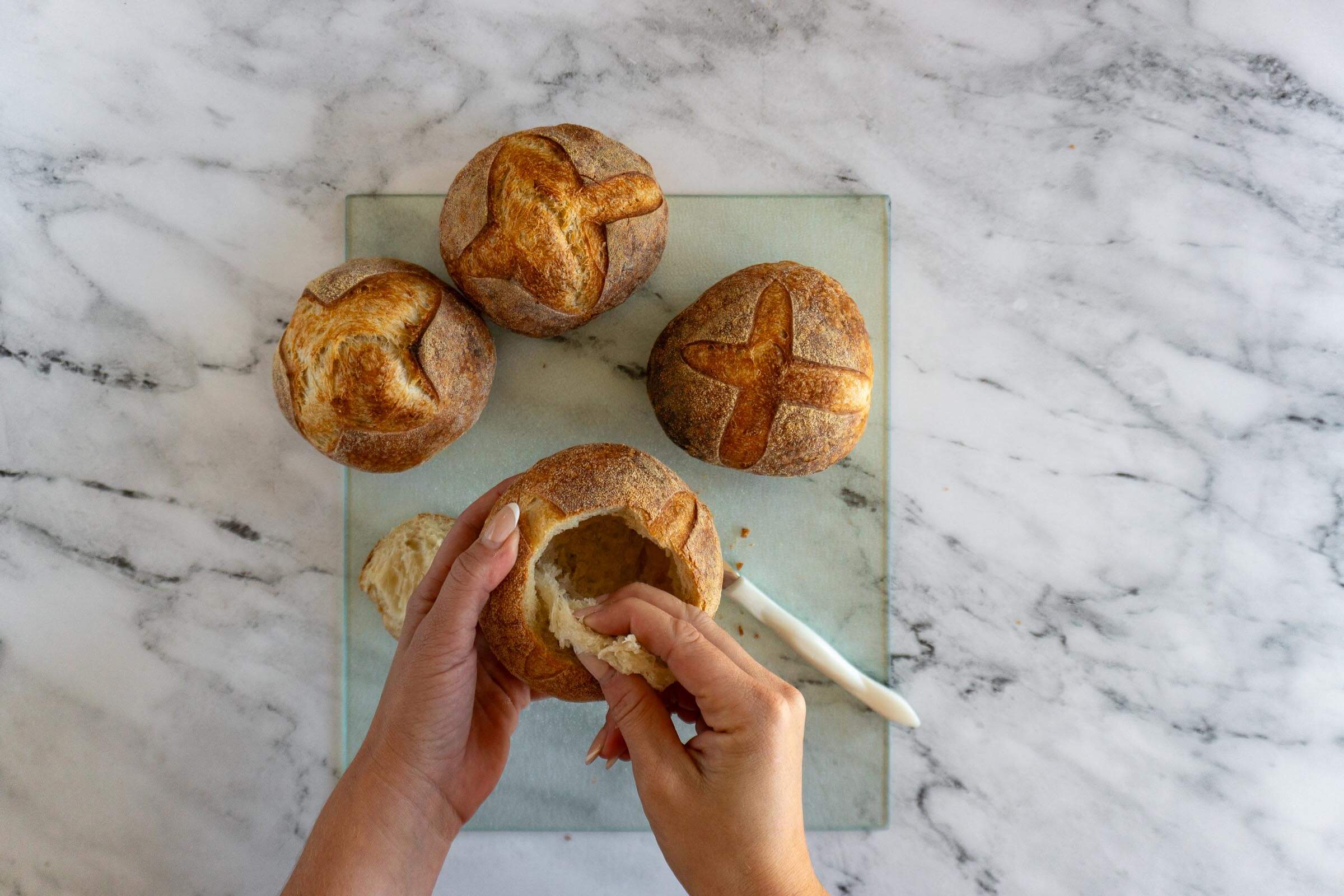 Hollowing out the insides of the cut bread bowl.