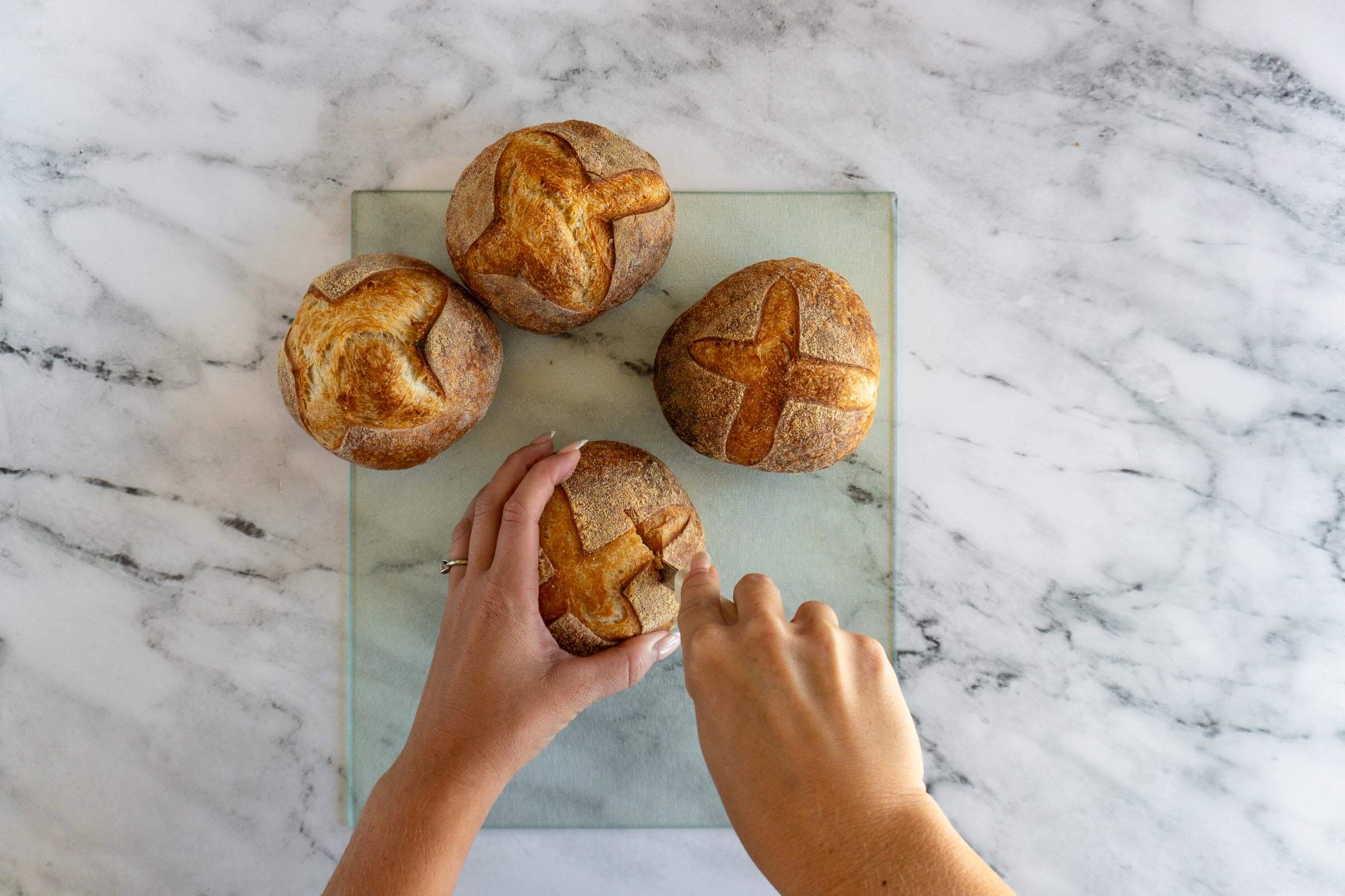 Slicing the top of a bread bowl with a serrated knife.