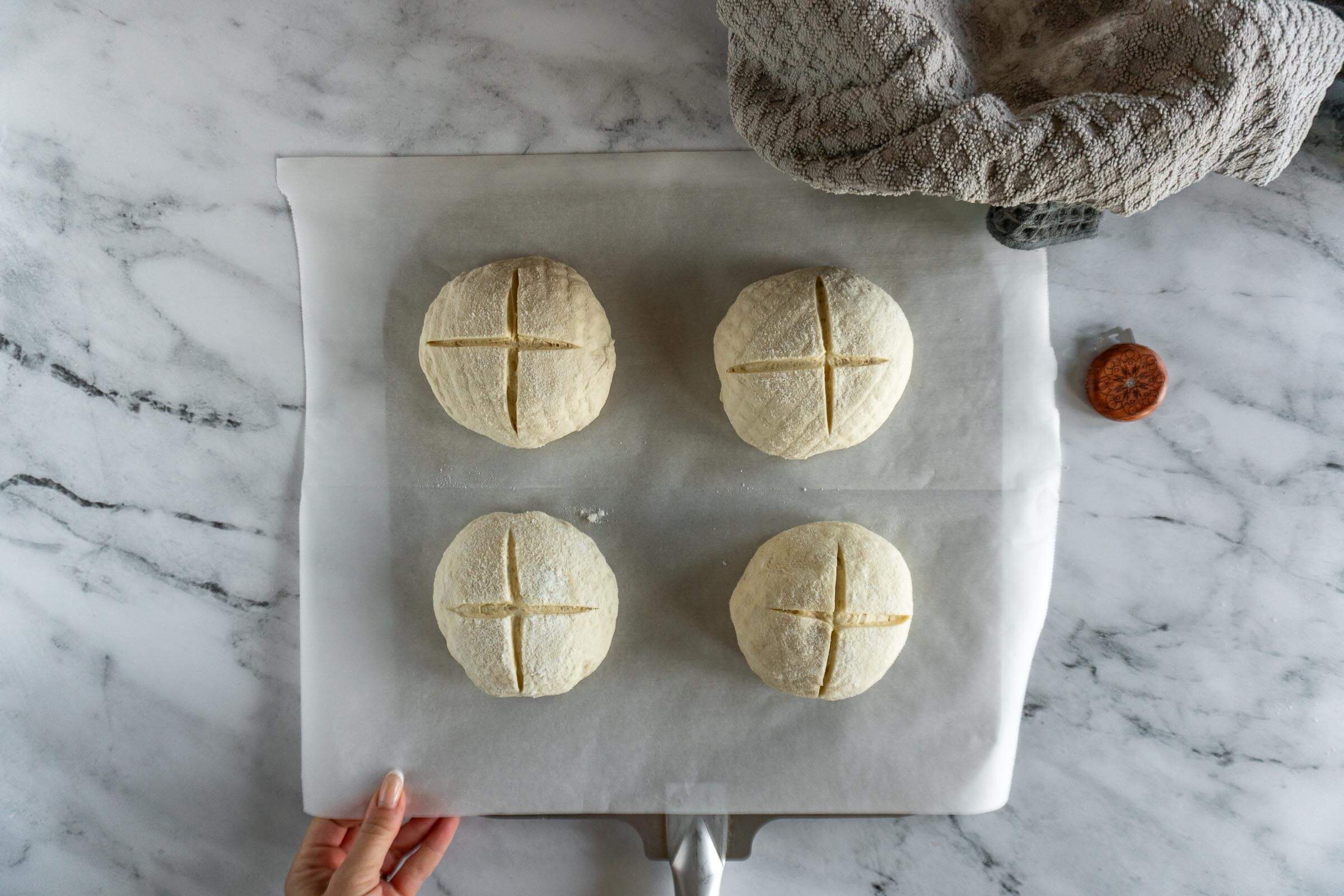 Loading parchment paper with four bread bowls onto pizza peel.