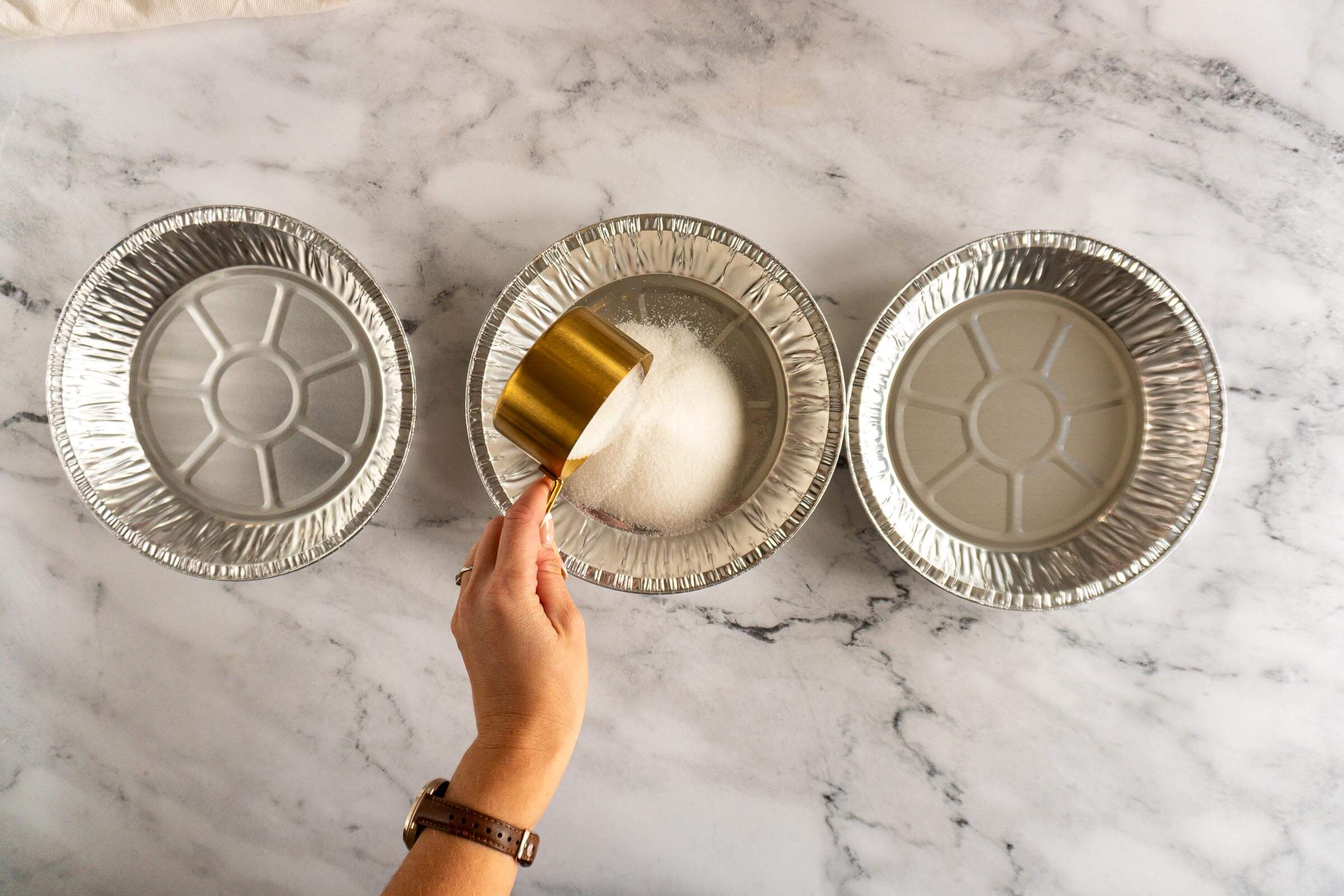 Adding granulated sugar to a pie plate. 