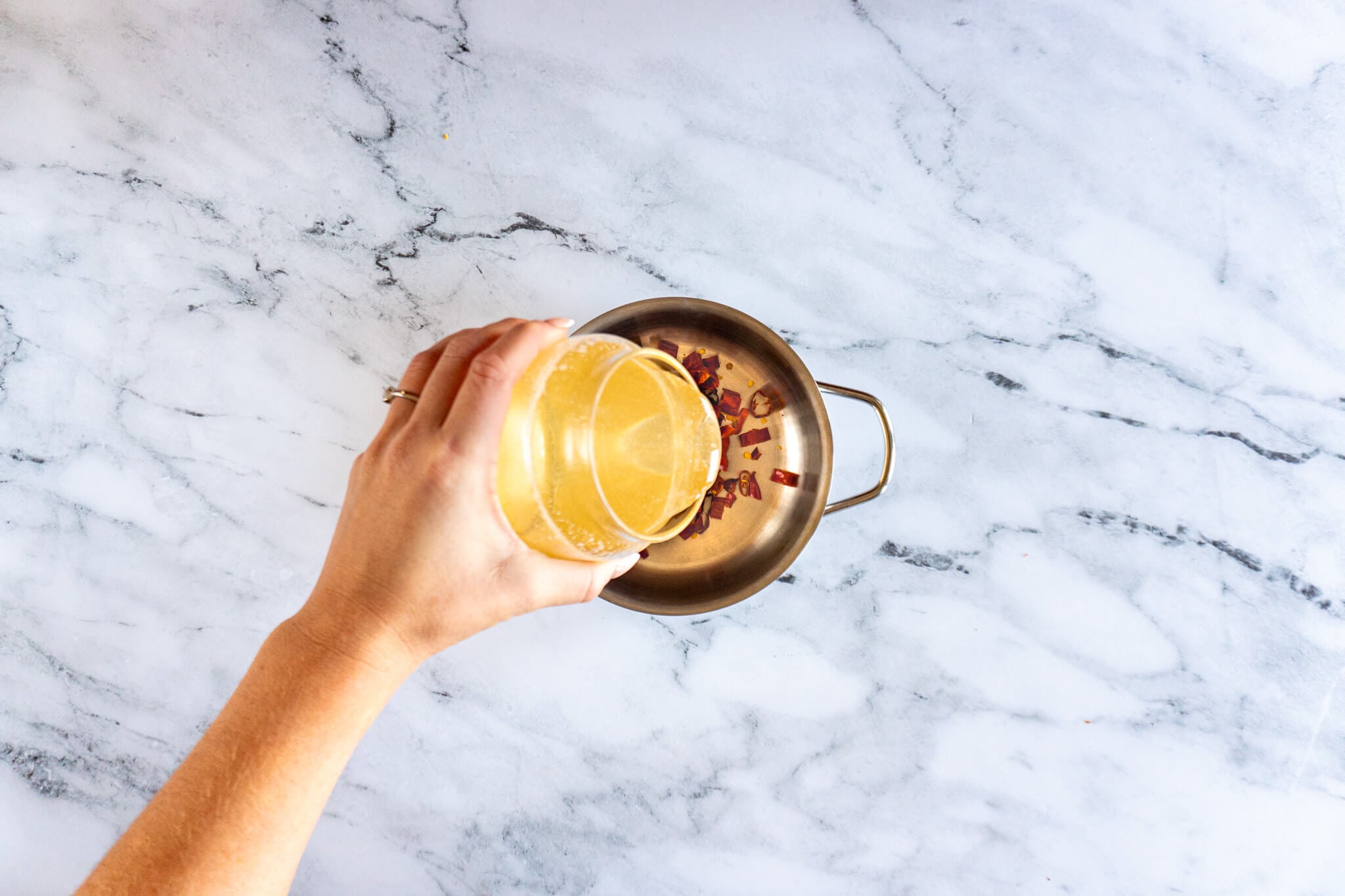 Pouring raw honey into a small saucepan. 