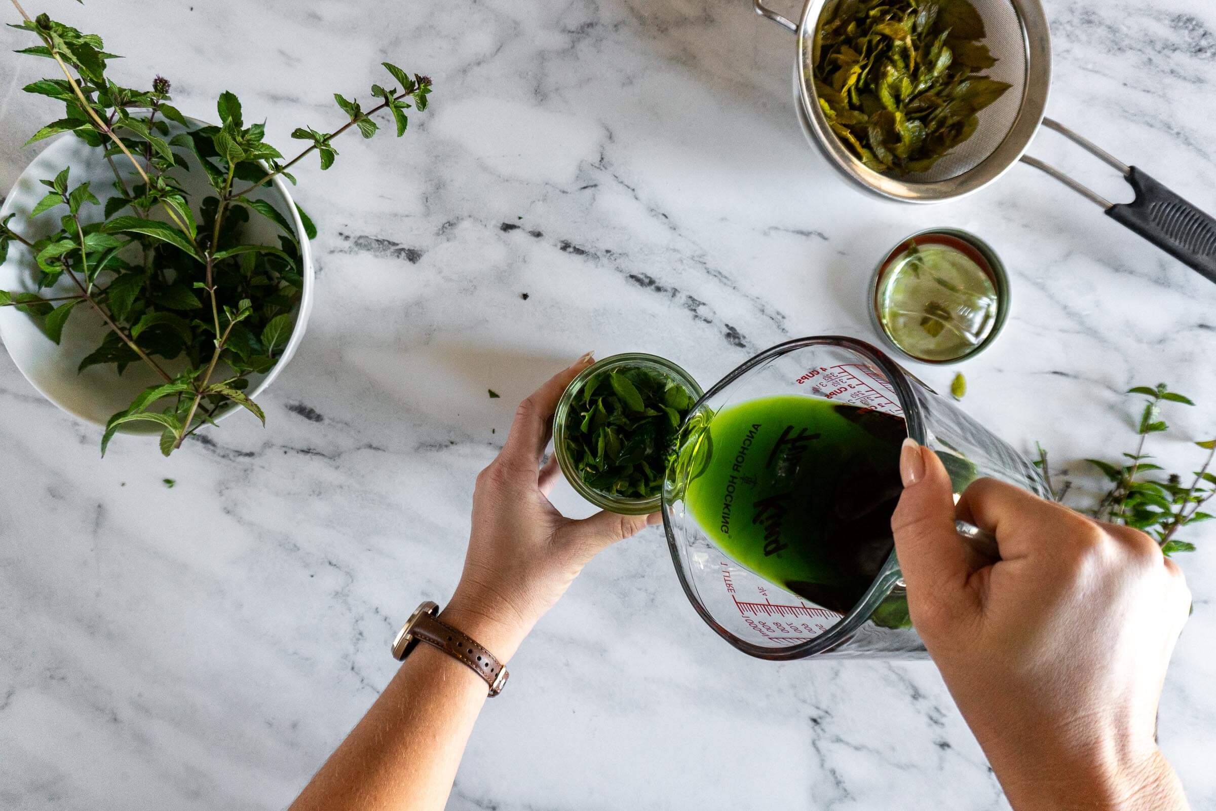 Pouring green mint infused alcohol over the leaves.