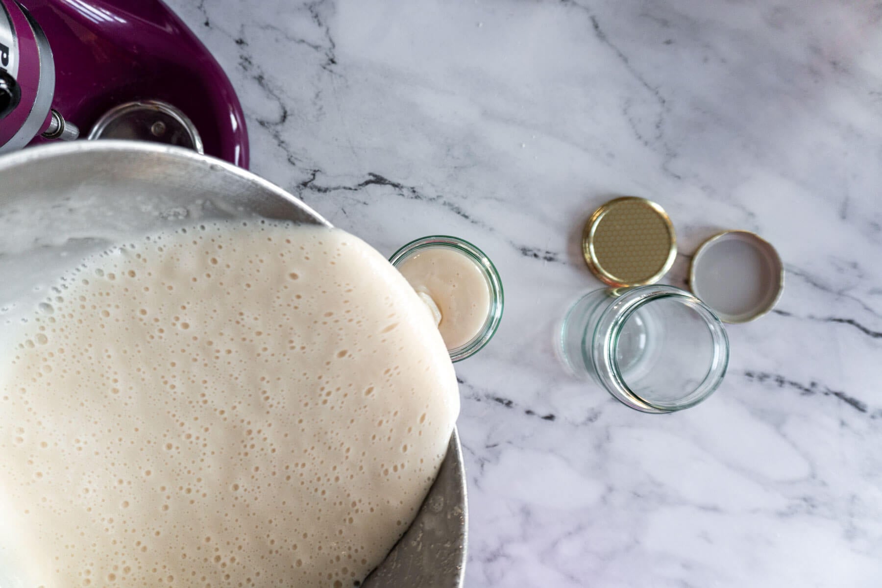 Pouring creamed honey into glass jars. 