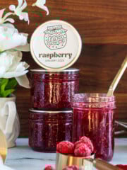Raspberry jam in a mason jar with gold knife.