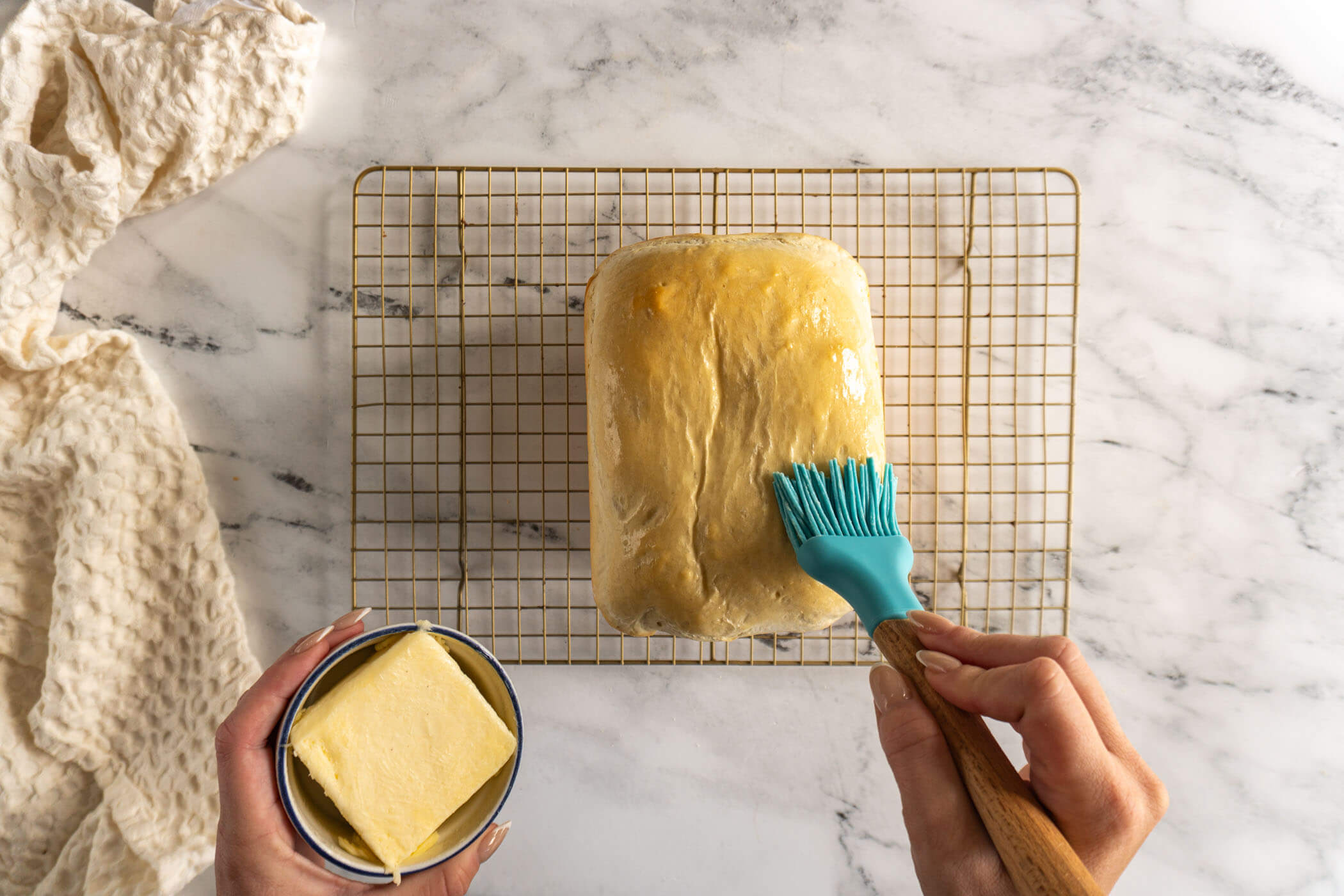 Brushing butter on a freshly baked bread machine sourdough loaf. 