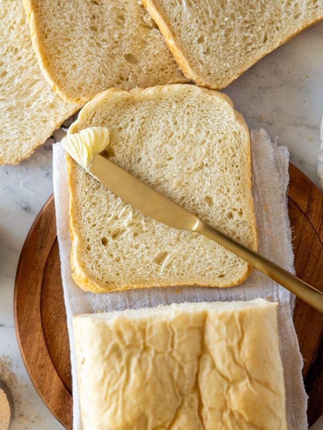 Sliced bread machine sourdough bread with a pat of butter.