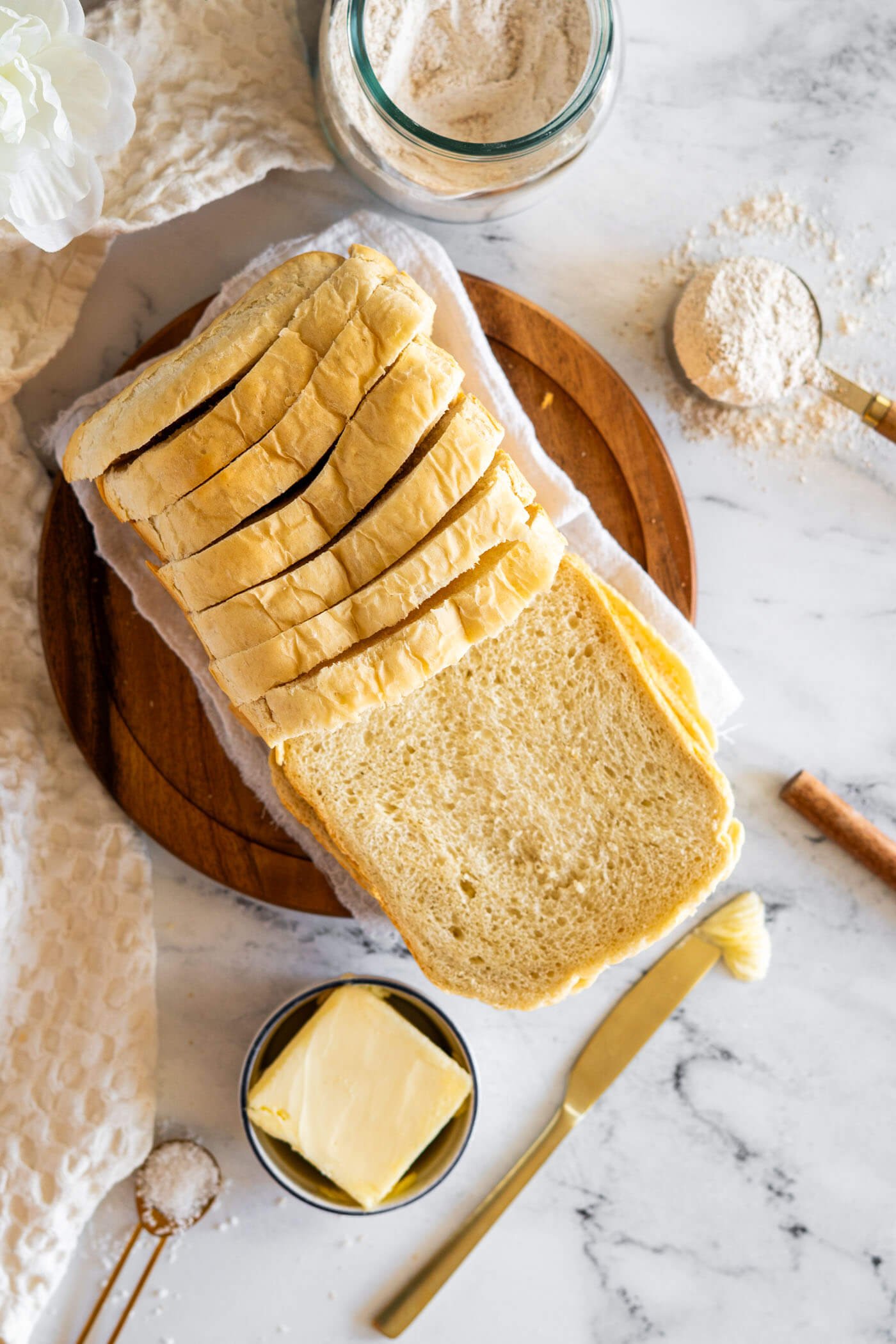 Sliced bread machine sourdough bread on a round wooden cutting board.